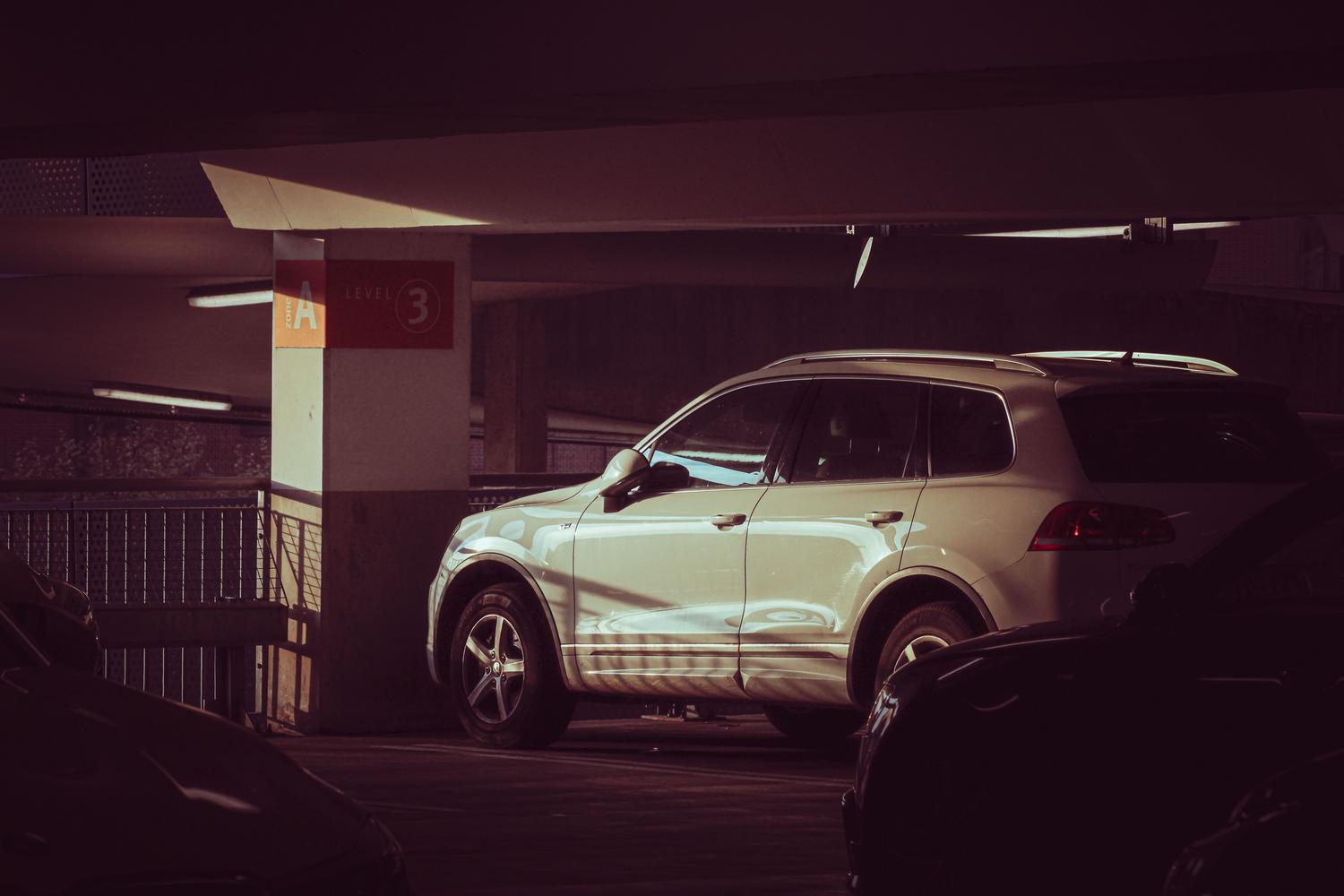 Coche blanco localizado en un parking interior con señalización clara de zona y nivel.
