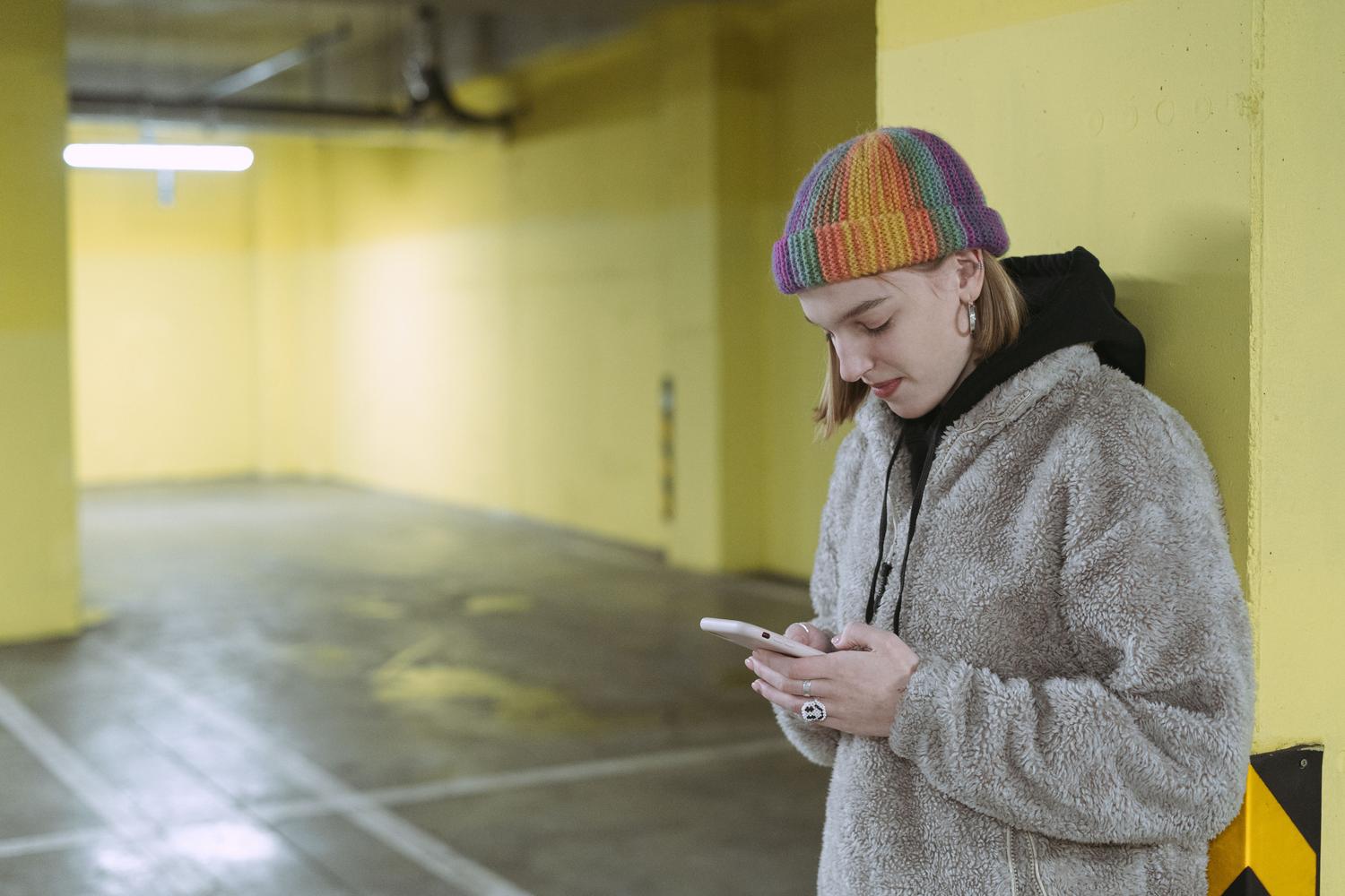 Mujer utilizando un smartphone en un parking subterráneo para registrar la ubicación de su coche.