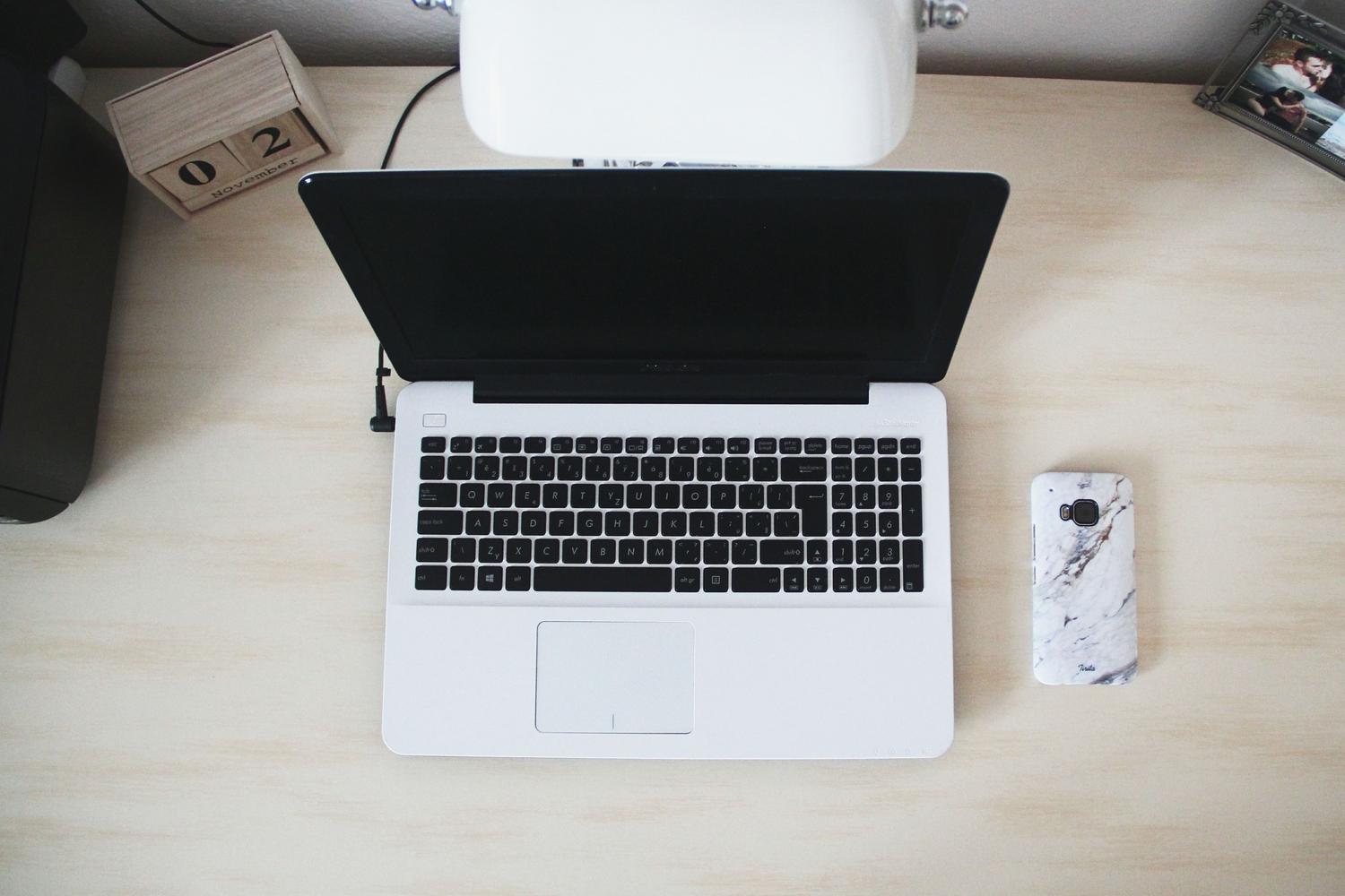 Espacio de trabajo minimalista con un ordenador portátil y un smartphone, perfecto para la sección de gestión de cuentas desde PC.