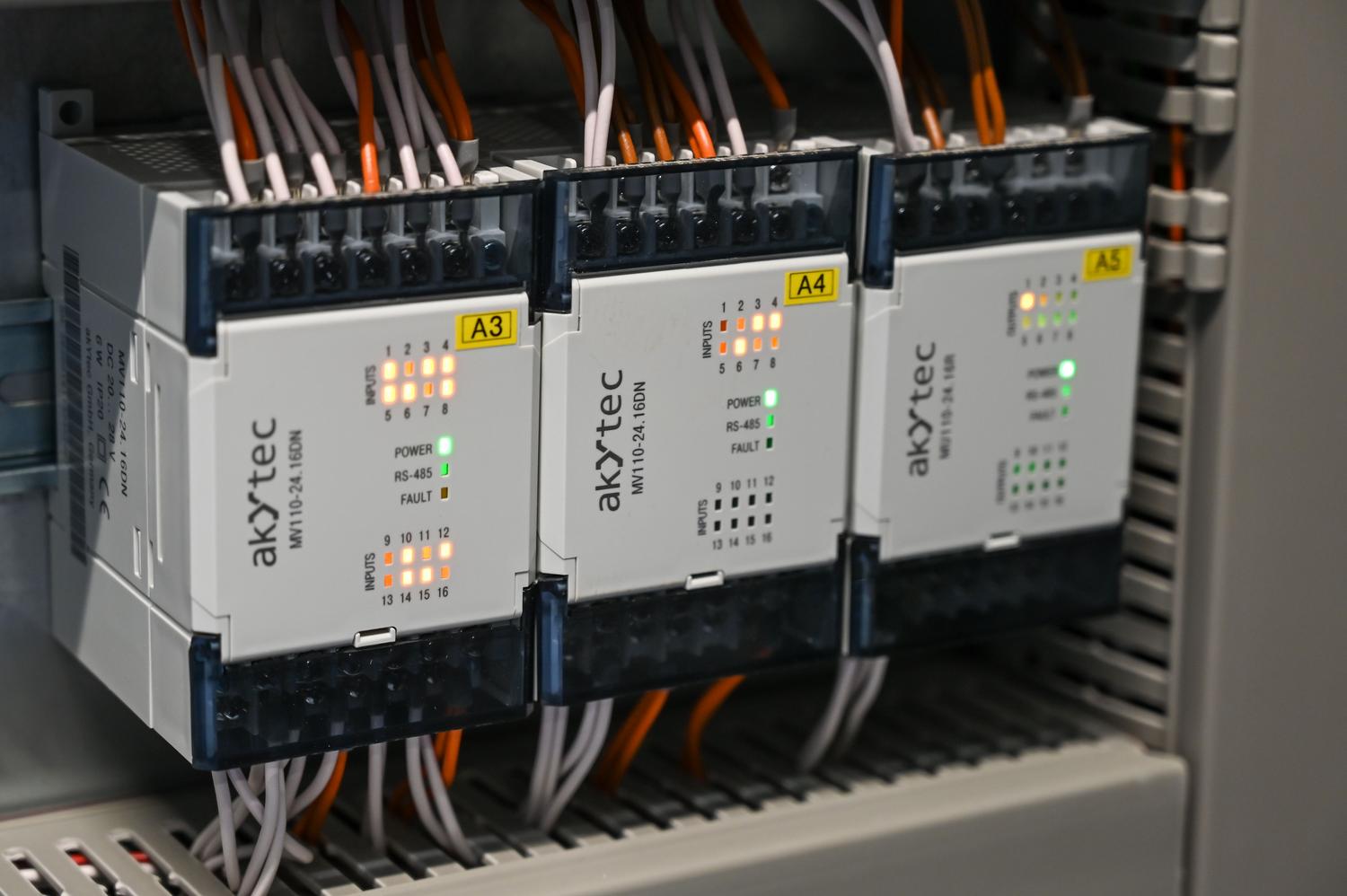 Módulos de entrada y salida de un controlador lógico programable (PLC) instalados en un armario eléctrico industrial.