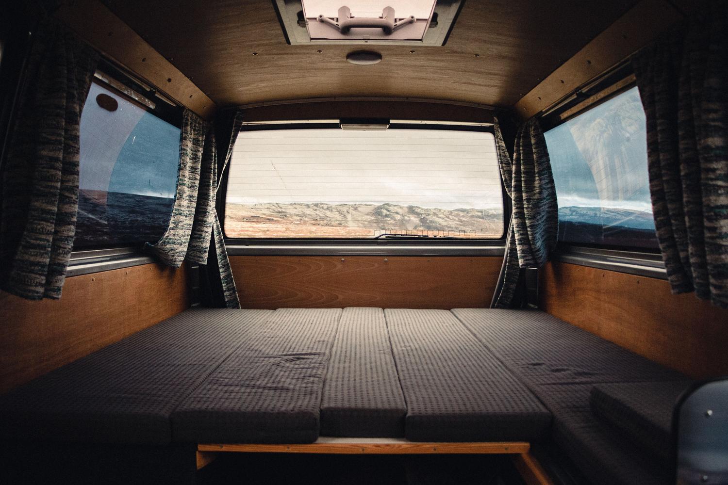 Interior espacioso y acogedor de una furgoneta camper con vistas a un paisaje natural, ideal para ilustrar el equipamiento técnico y el diseño funcional. Interior espacioso y acogedor de una furgoneta camper con vistas a un paisaje natural, ideal para ilustrar el equipamiento técnico y el diseño funcional.