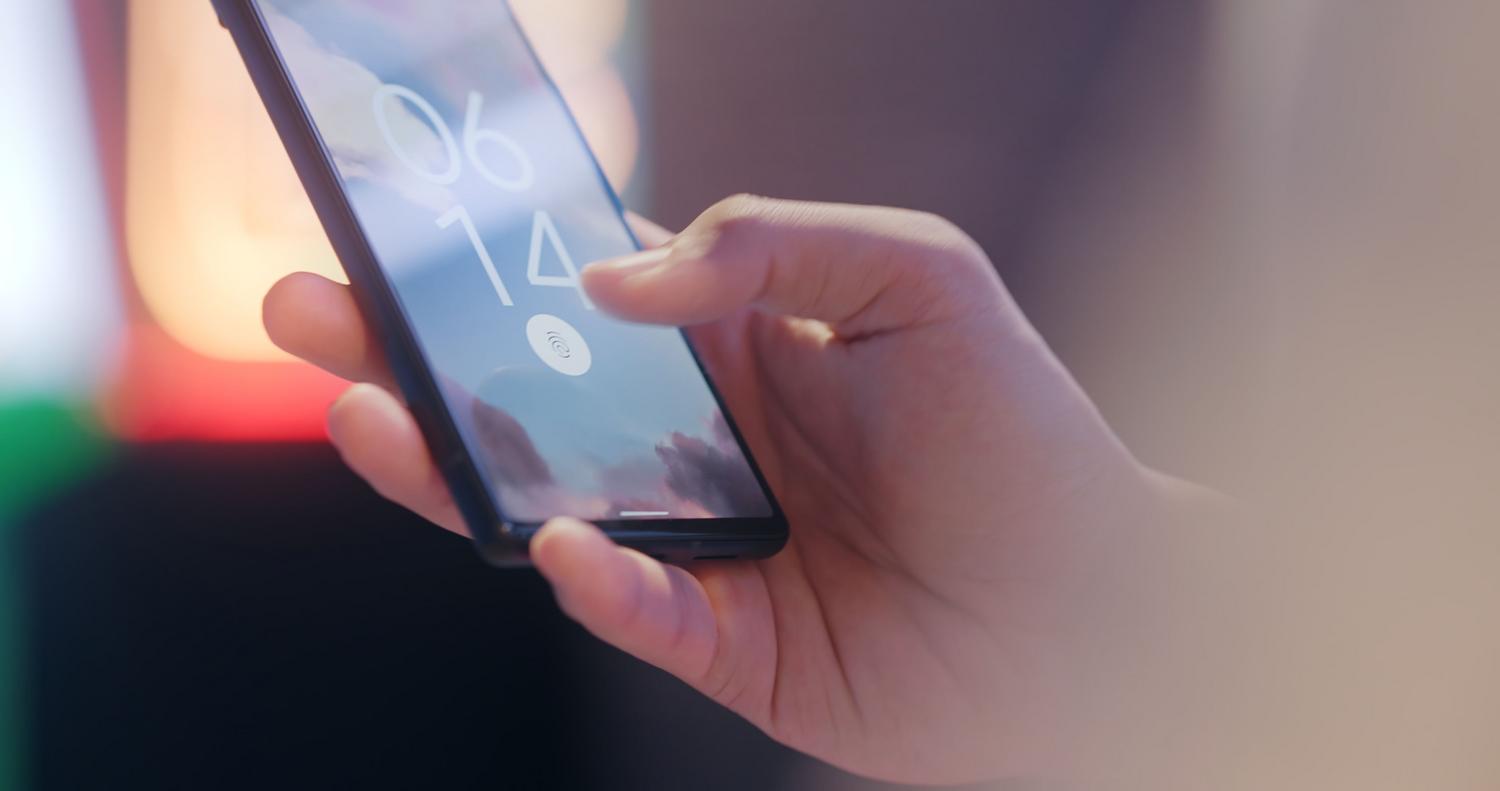 A hand using the fingerprint sensor to unlock a modern Android smartphone, showcasing biometric security features.