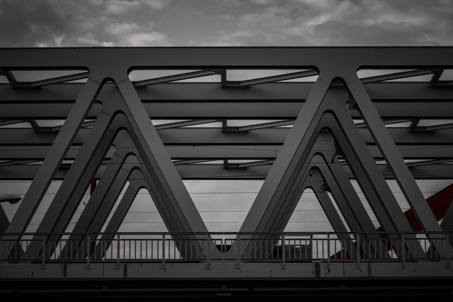 Detalle de vigas de acero y estructuras triangulares de un puente moderno, ilustrando la ingeniería estructural y la distribución de cargas.