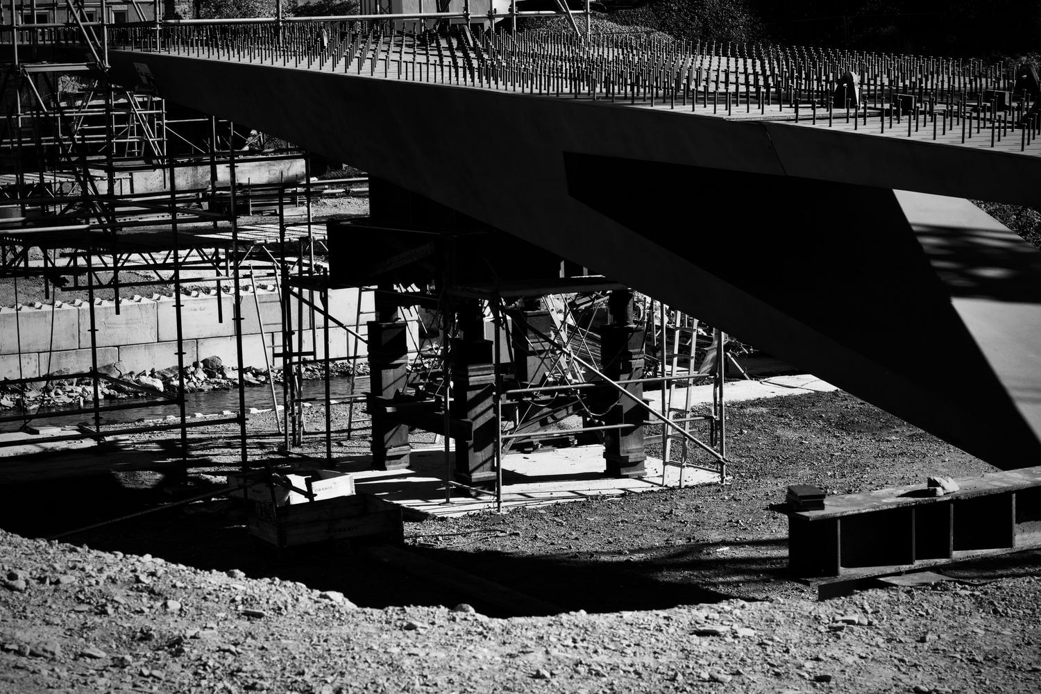 Vista de un puente en construcción con andamios y armaduras de acero, representando la fase de planificación y la estructura básica de la obra.