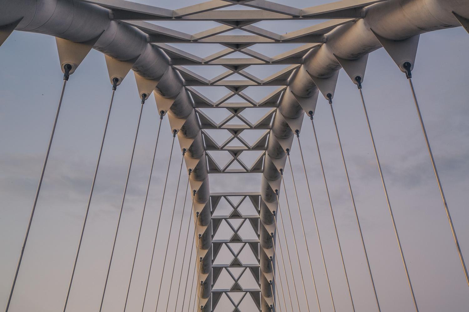 Diseño arquitectónico futurista de un puente de acero visto desde abajo, representando la creatividad y los diseños complejos del modo sandbox.