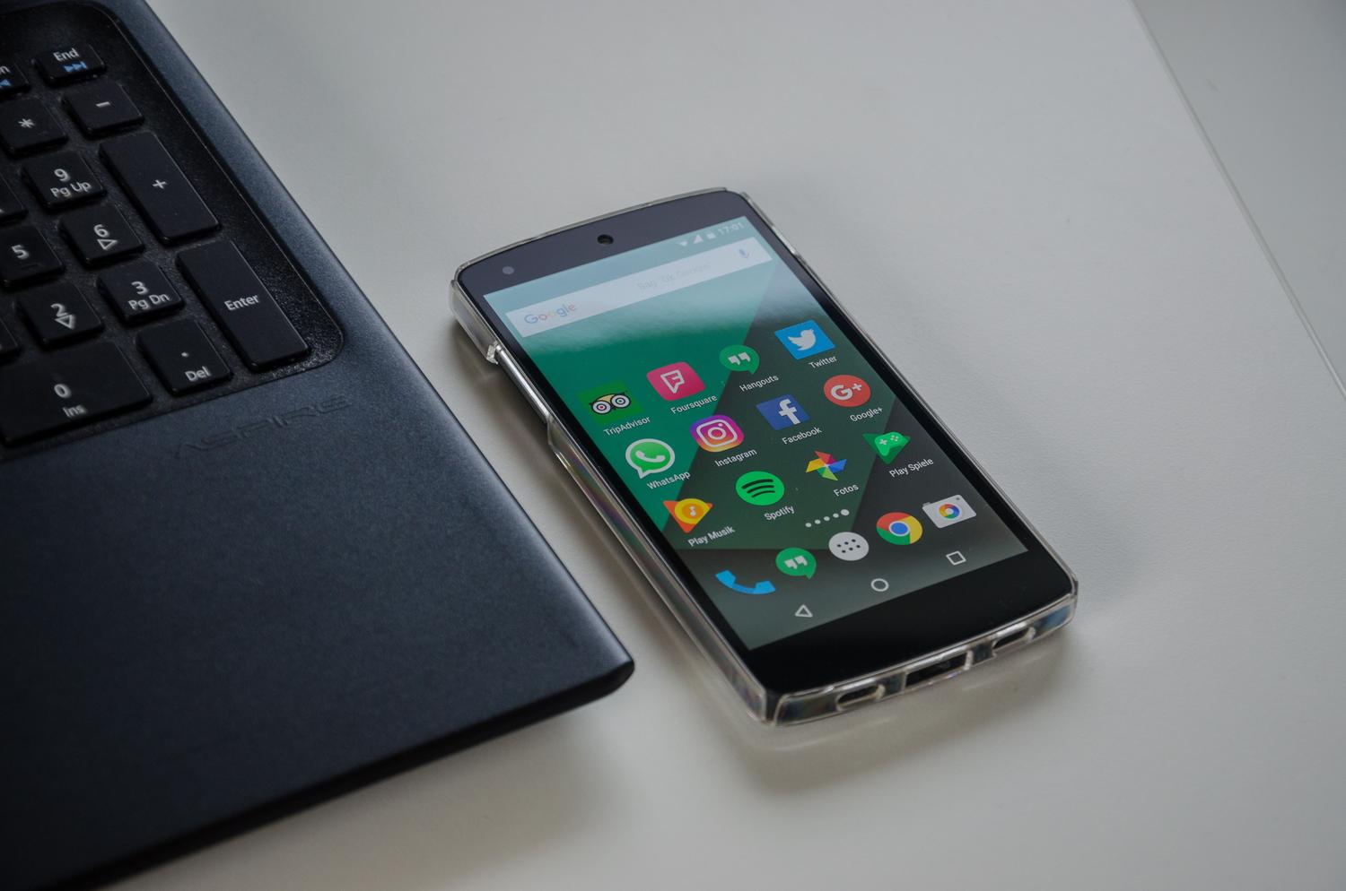 Un smartphone y un portátil sobre un escritorio limpio, representando el ecosistema de desarrollo de aplicaciones móviles.