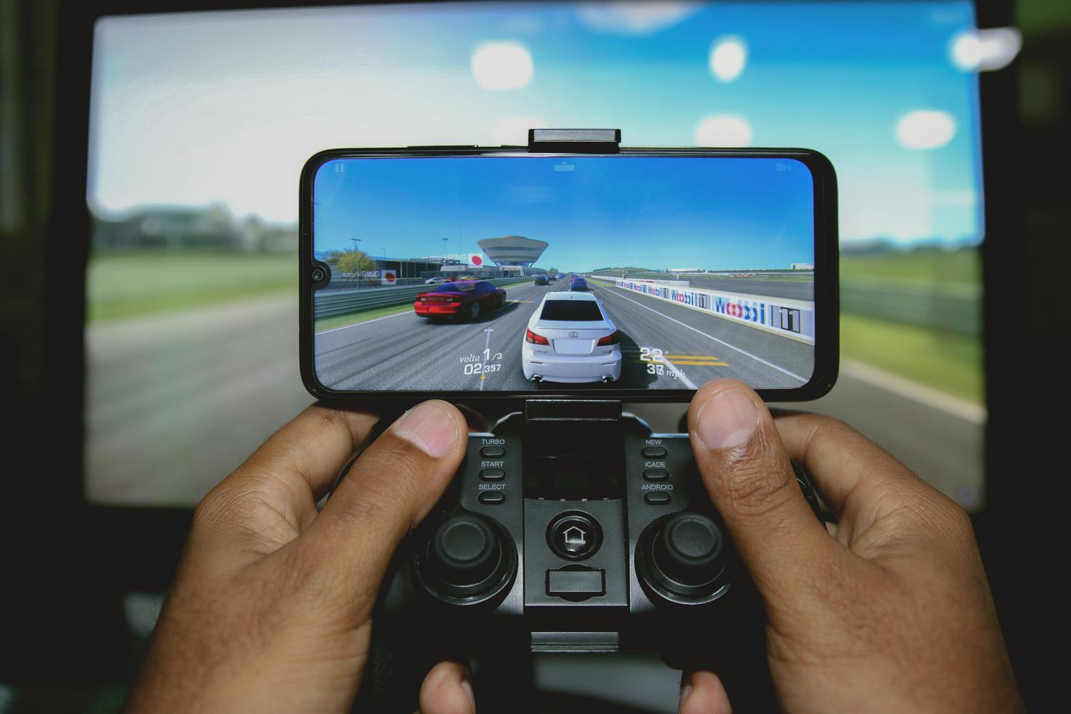 Persona utilizando un mando externo para jugar a un juego de carreras de alta fidelidad en Android, destacando la fluidez y potencia del sistema.
