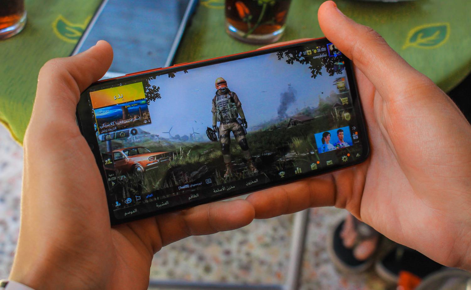 Jugador disfrutando de una partida competitiva de Battle Royale en su smartphone desde una terraza, representando el aspecto competitivo y los logros.