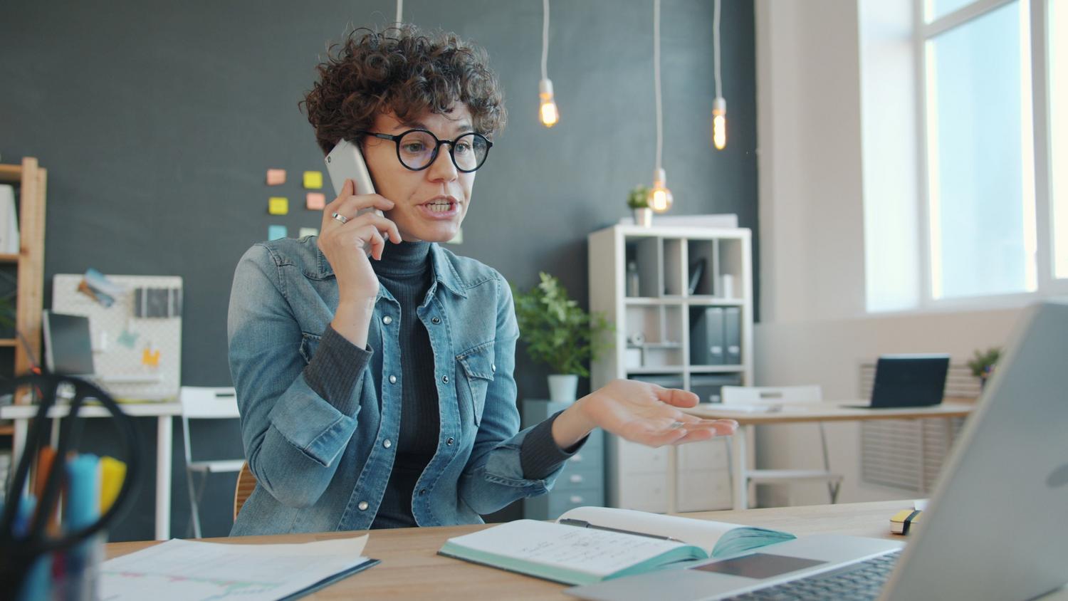 Mujer profesional en una llamada telefónica en una oficina contemporánea, representando la esencia humana en la comunicación empresarial.