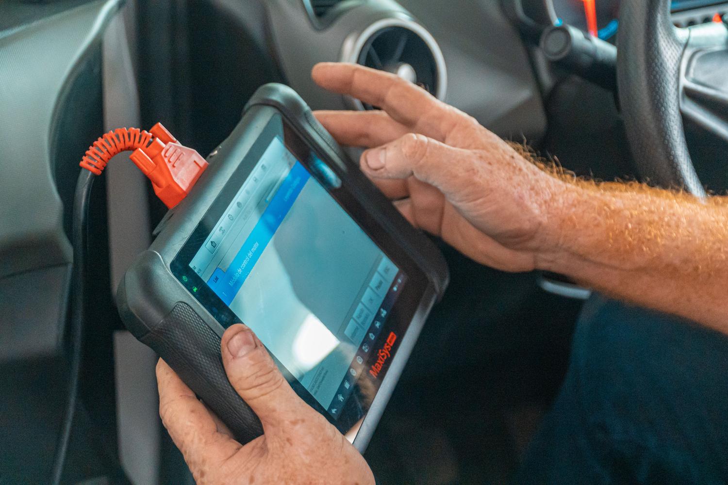 Técnico profesional utilizando una tablet de diagnóstico en el interior de un coche para analizar fallos del sistema de inmovilización.