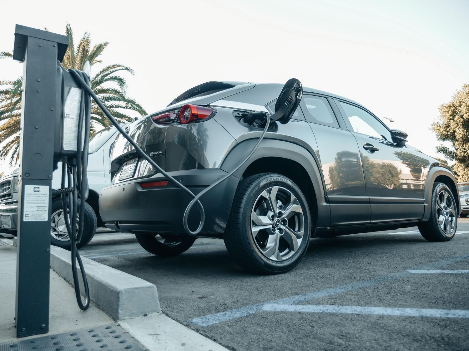 Coche eléctrico moderno cargando en una estación exterior durante el día.