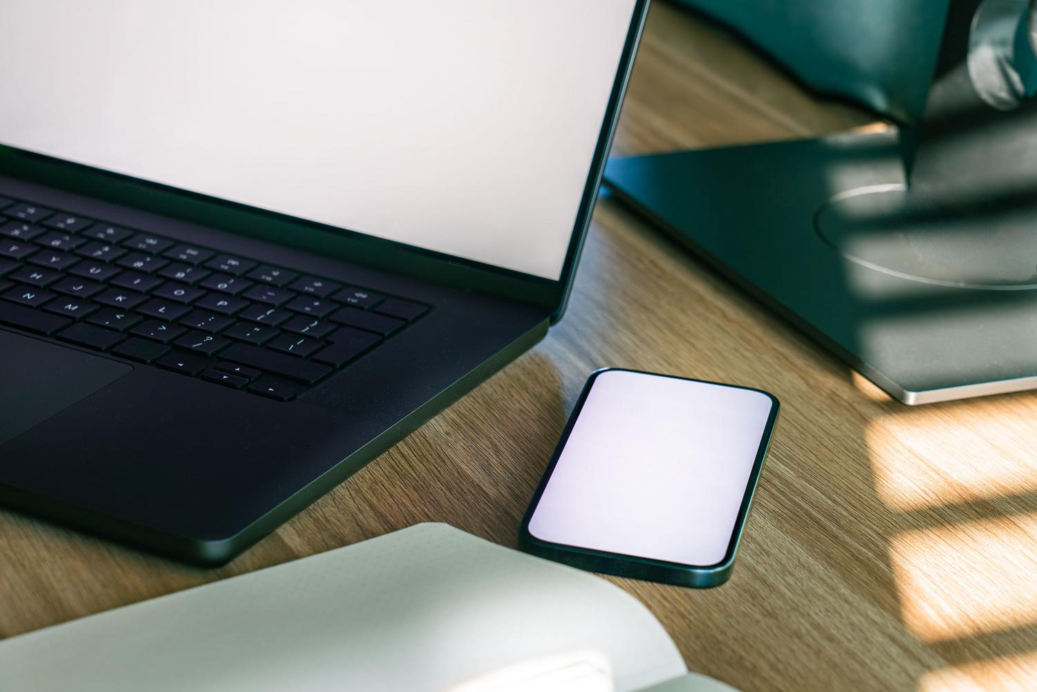 Espacio de trabajo minimalista con ordenador portátil y smartphone, ilustrando la productividad y movilidad del software SaaS.
