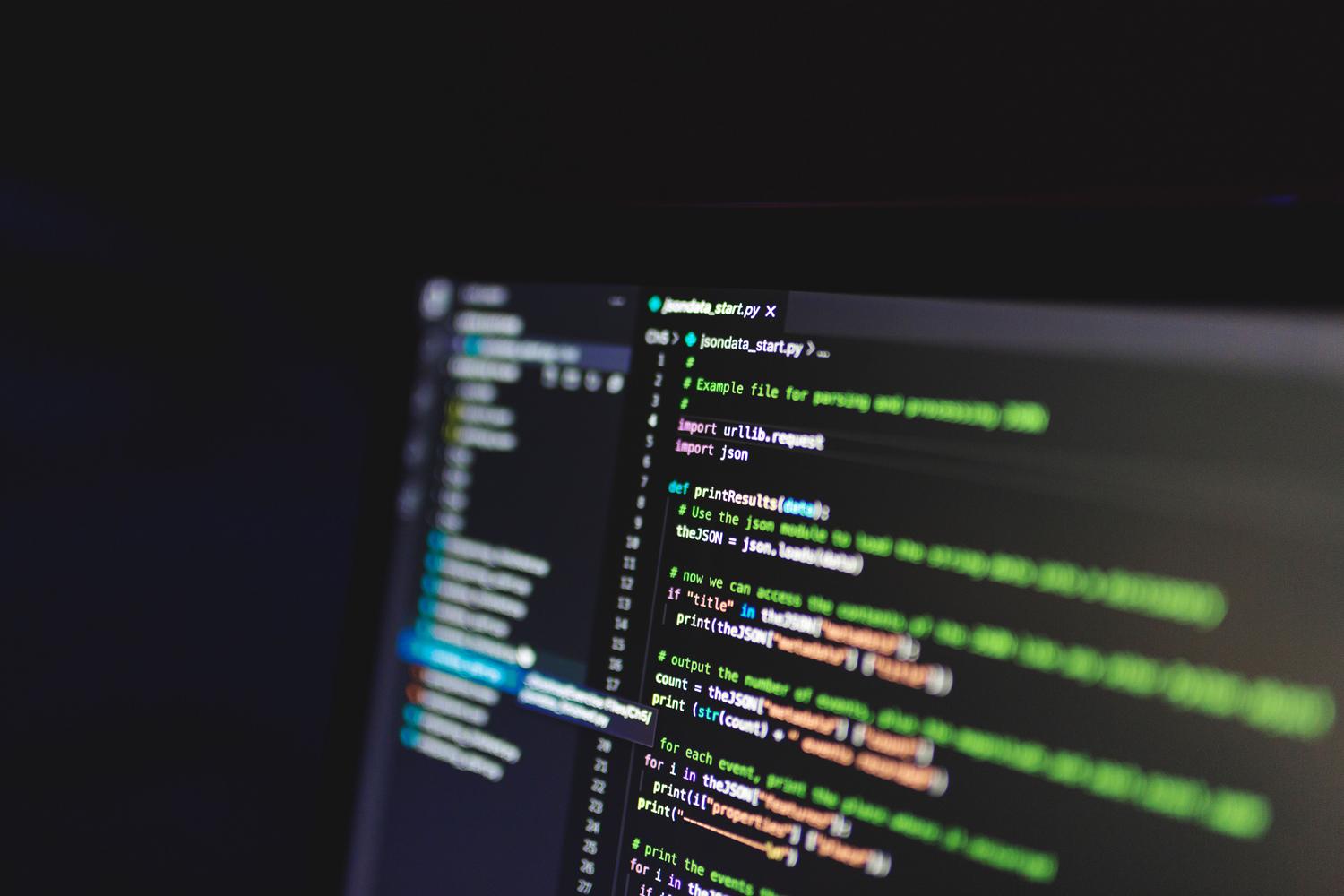 Primer plano de código de programación en una pantalla con modo oscuro, representando las capacidades de generación y depuración de código de Copilot.