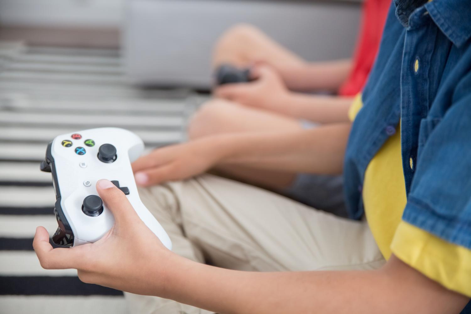 Dos niños jugando juntos con mandos de consola, ilustrando la sociabilidad y el uso de servidores privados en Roblox Plus.