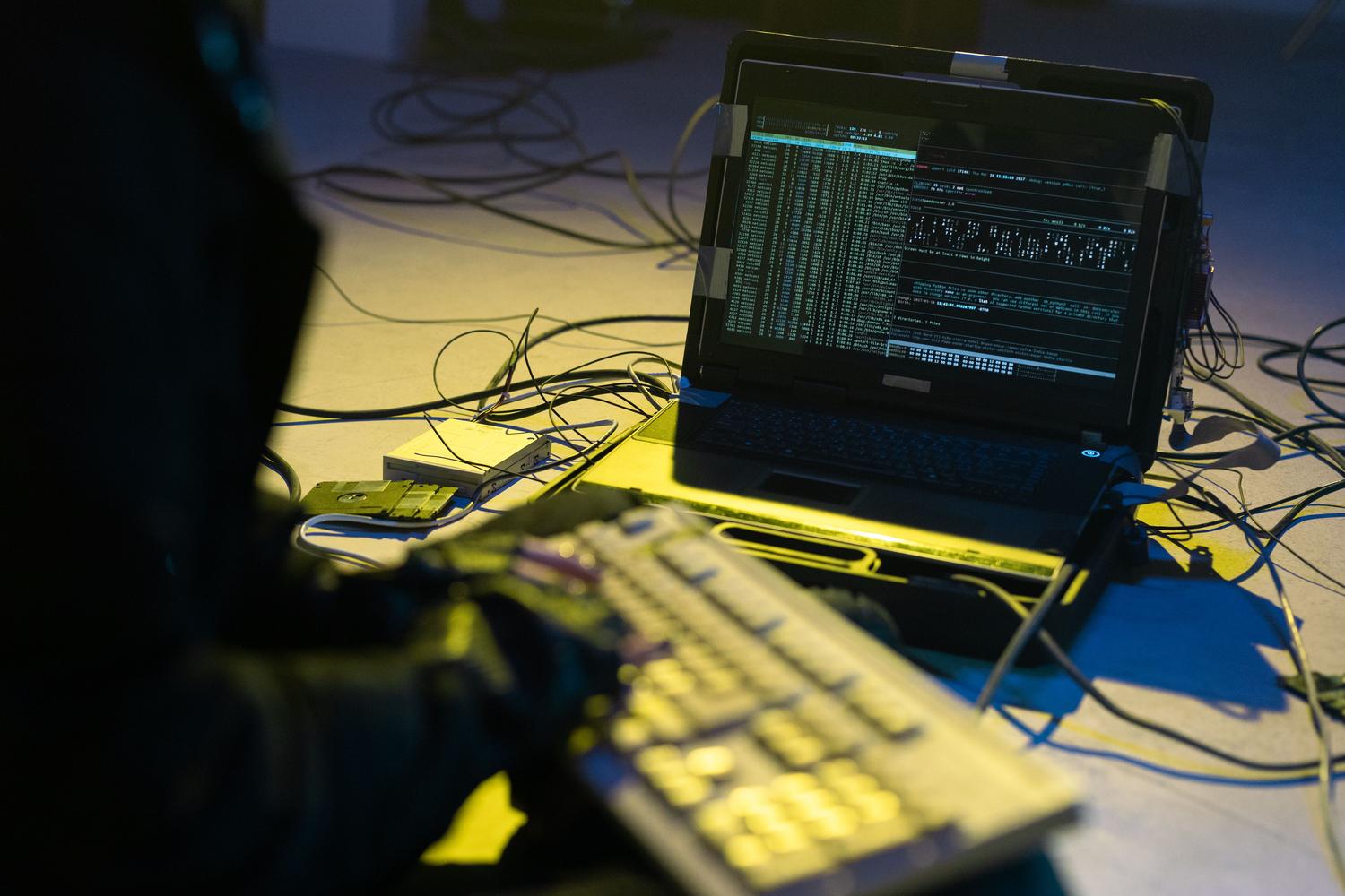 Primer plano de una persona programando en un portátil rodeada de cables, representando la naturaleza programable de las Redes Definidas por Software.