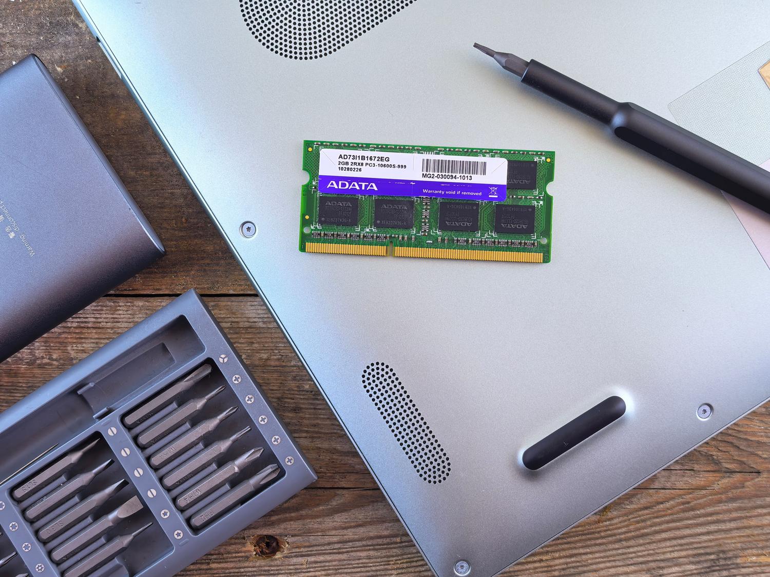 Portátil abierto mostrando el módulo de RAM y herramientas de reparación, ideal para ilustrar la ampliación de memoria.