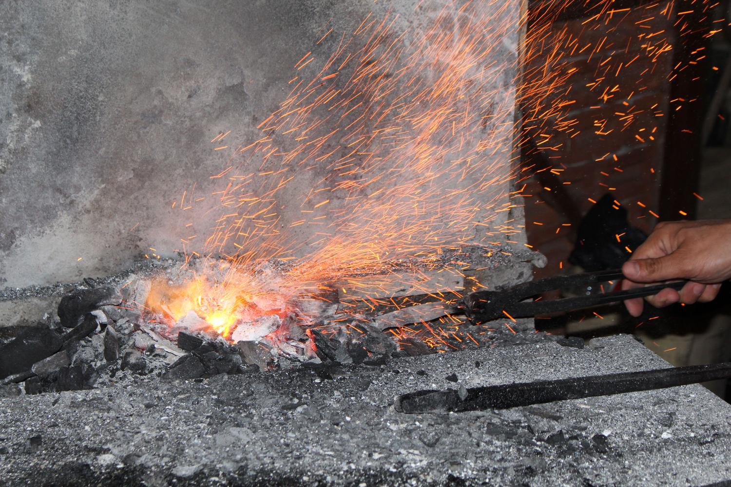 Traditional blacksmith forge with sparks flying, representing the game environment of The Forge