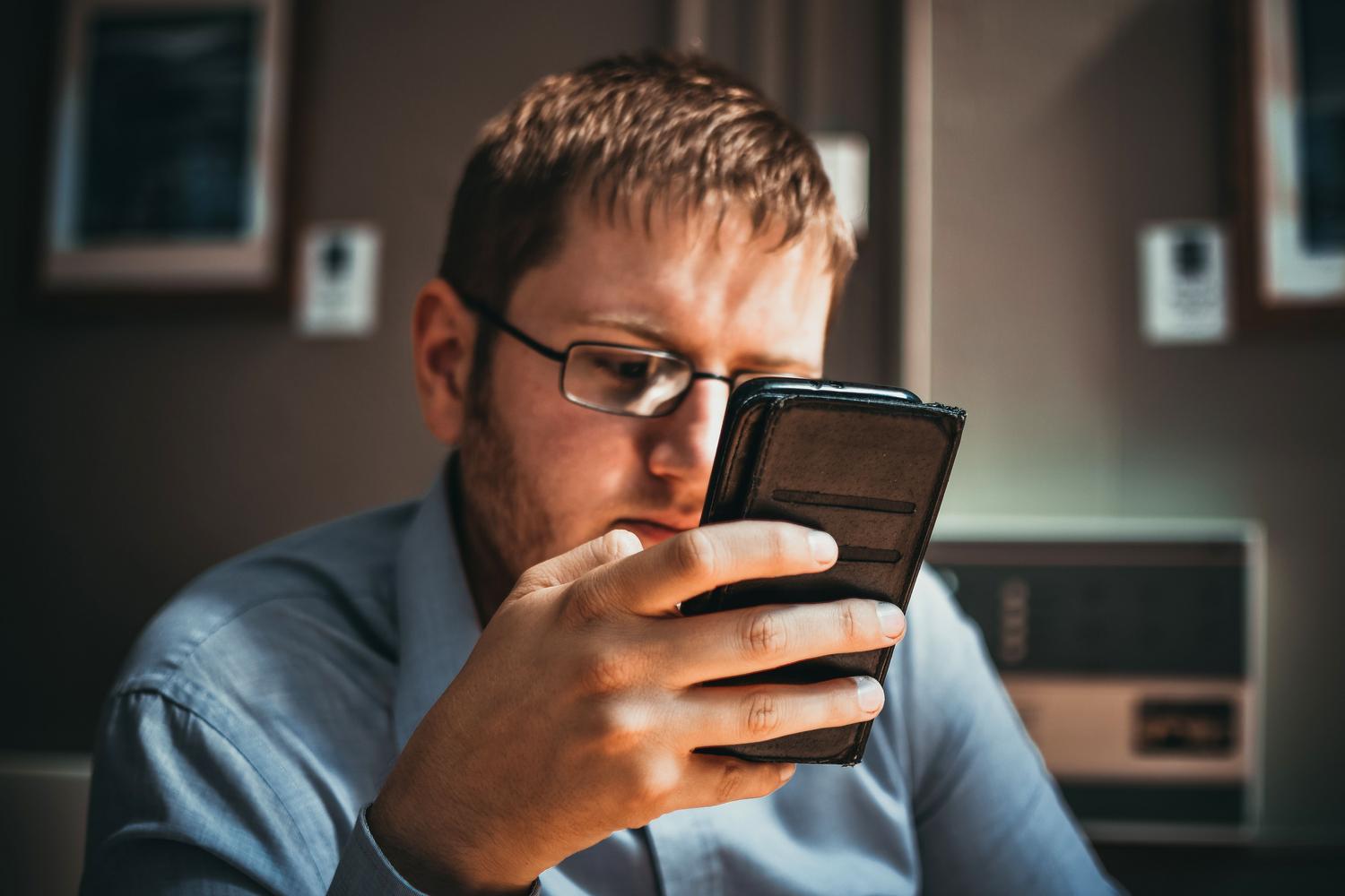Hombre de negocios revisando comunicaciones en su móvil, destacando la importancia de la identidad digital.