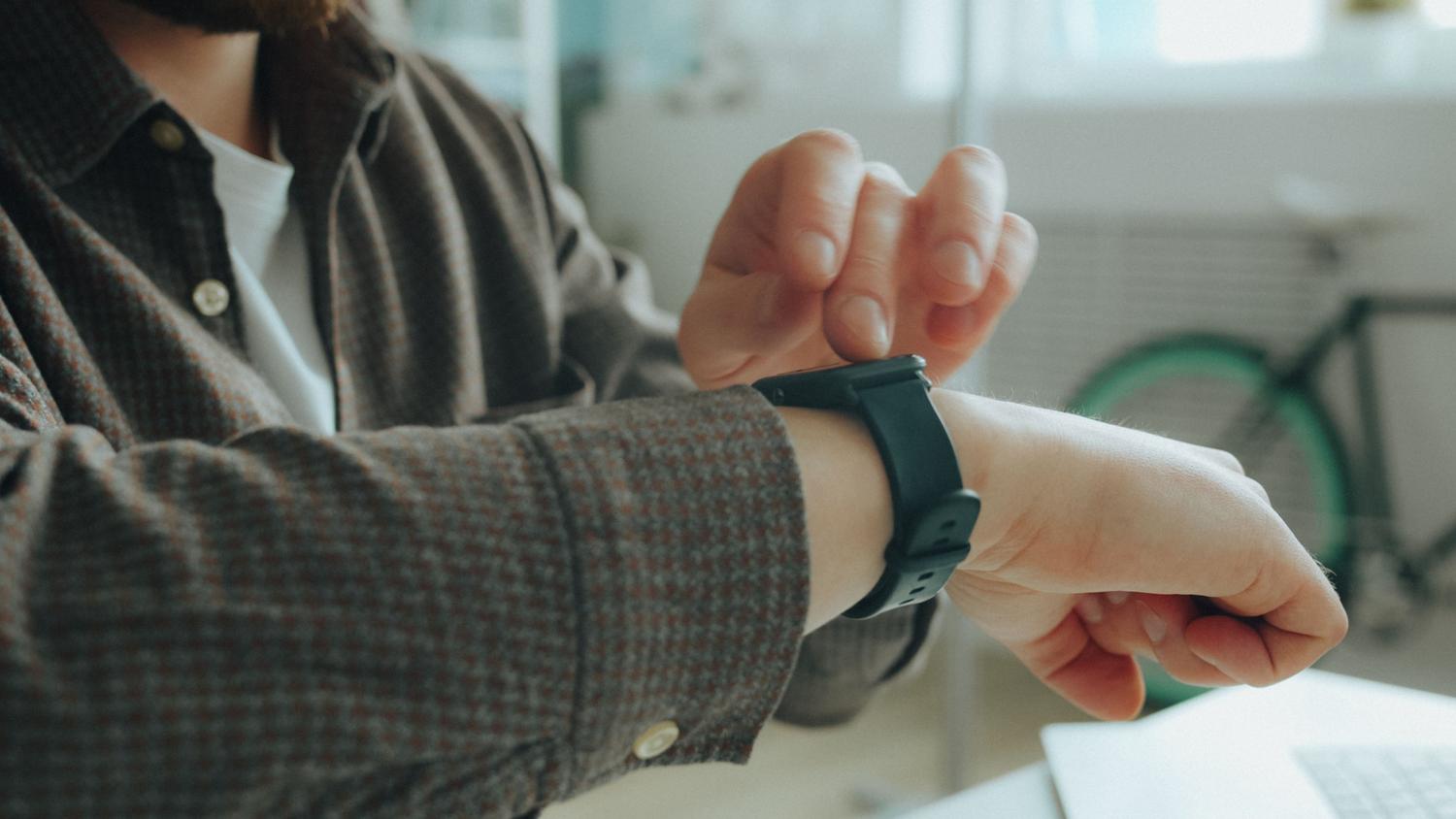 Persona ajustando su smartwatch en un entorno cotidiano, representando la experiencia de usuario fluida.