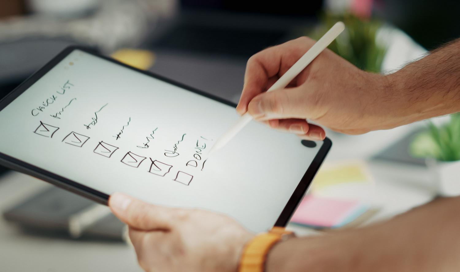 Mano utilizando un lápiz digital para marcar una checklist en una tablet, representando la digitalización de tareas y el primer paso hacia la productividad automatizada.