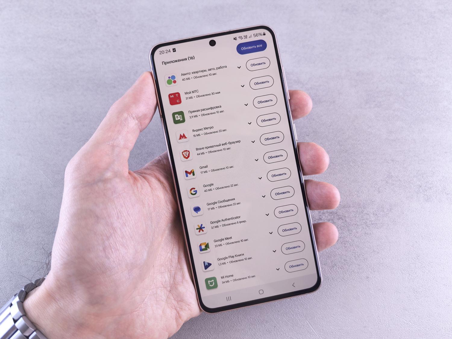 Mano sosteniendo un móvil con la lista de aplicaciones pendientes de actualizar en la tienda de apps.