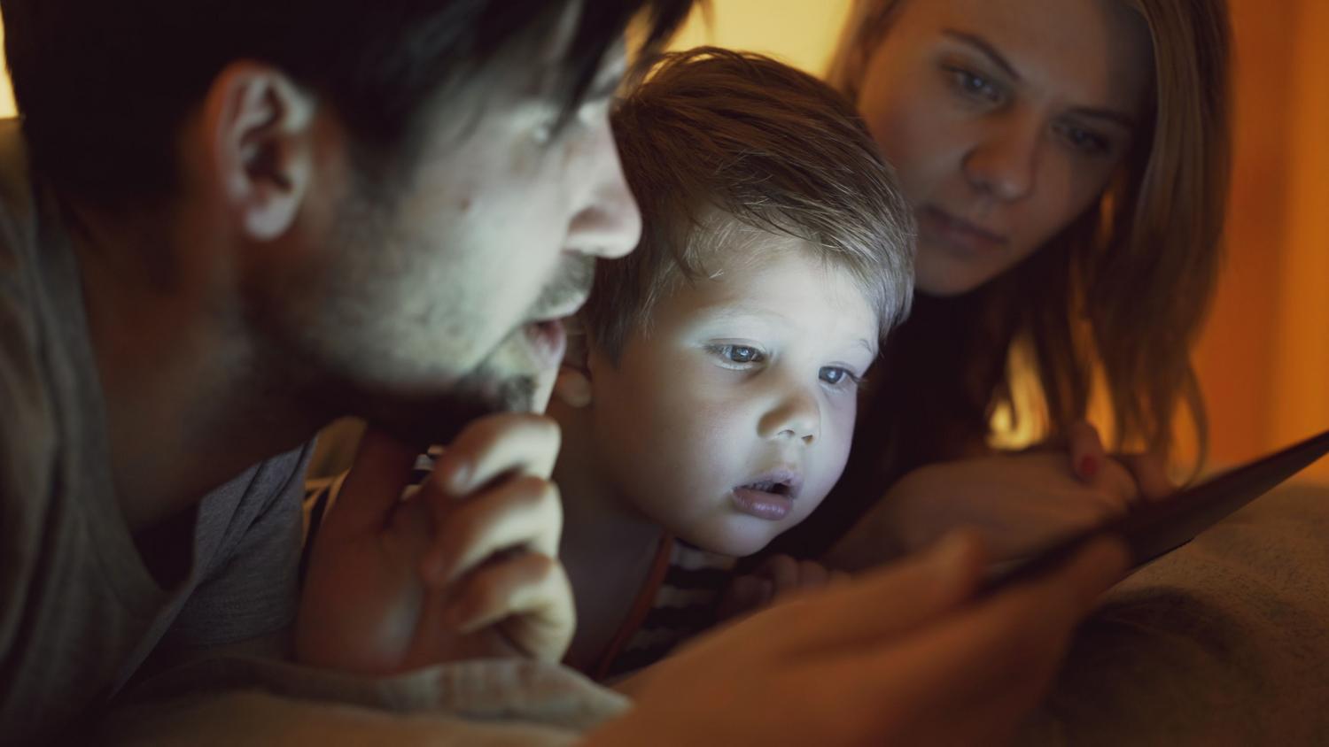 Familia reunida interactuando con un dispositivo digital, simbolizando el equilibrio entre tecnología y convivencia familiar.