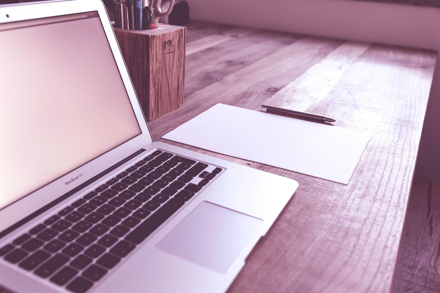 Espacio de trabajo minimalista y organizado con un portátil y papel, transmitiendo simplicidad y un flujo de trabajo optimizado.