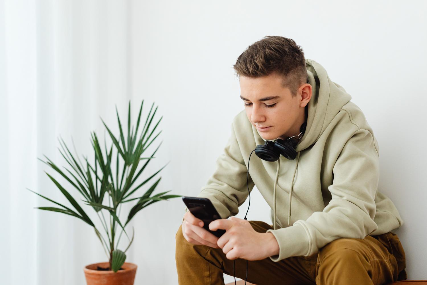 Joven adolescente con auriculares utilizando su móvil, simbolizando la autonomía digital.