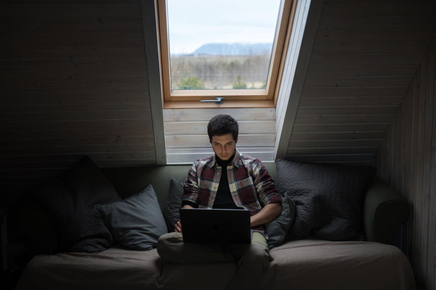Joven en un sofá usando un ordenador portátil para gestionar su cuenta de Netflix a través del navegador web.