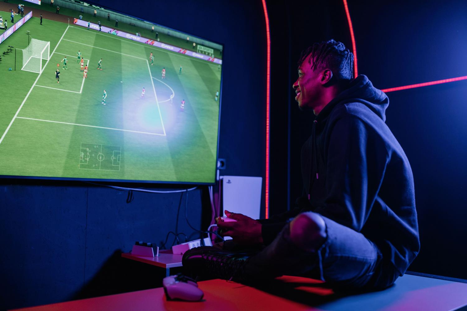 Joven concentrado jugando a la consola en una habitación con iluminación gaming neon