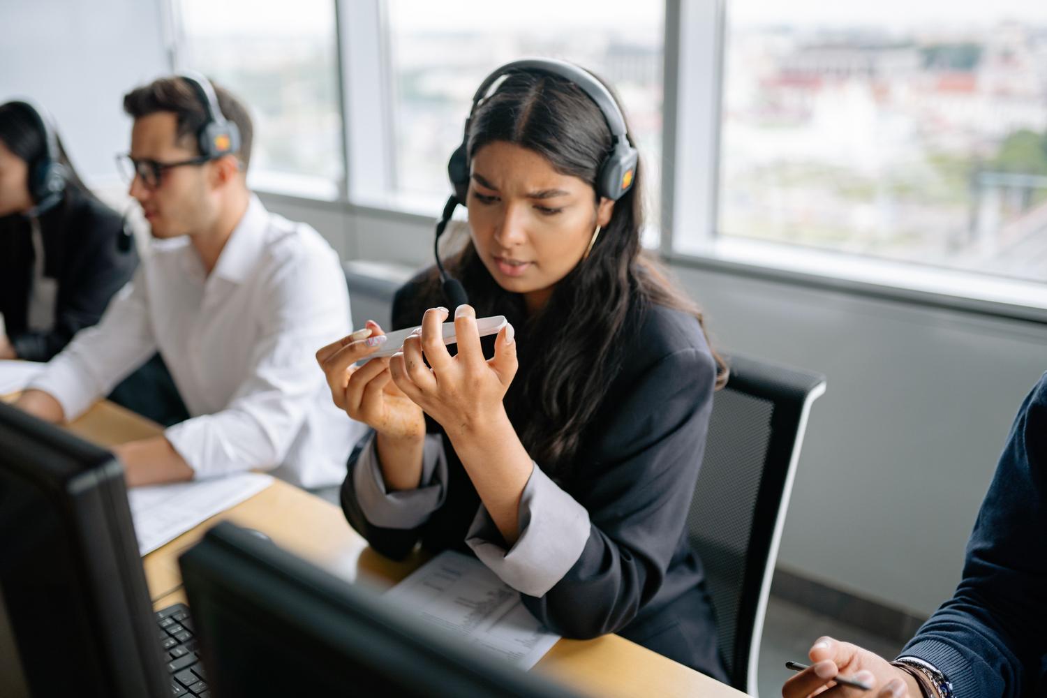 Agente de soporte al cliente con auriculares en un entorno de oficina profesional.