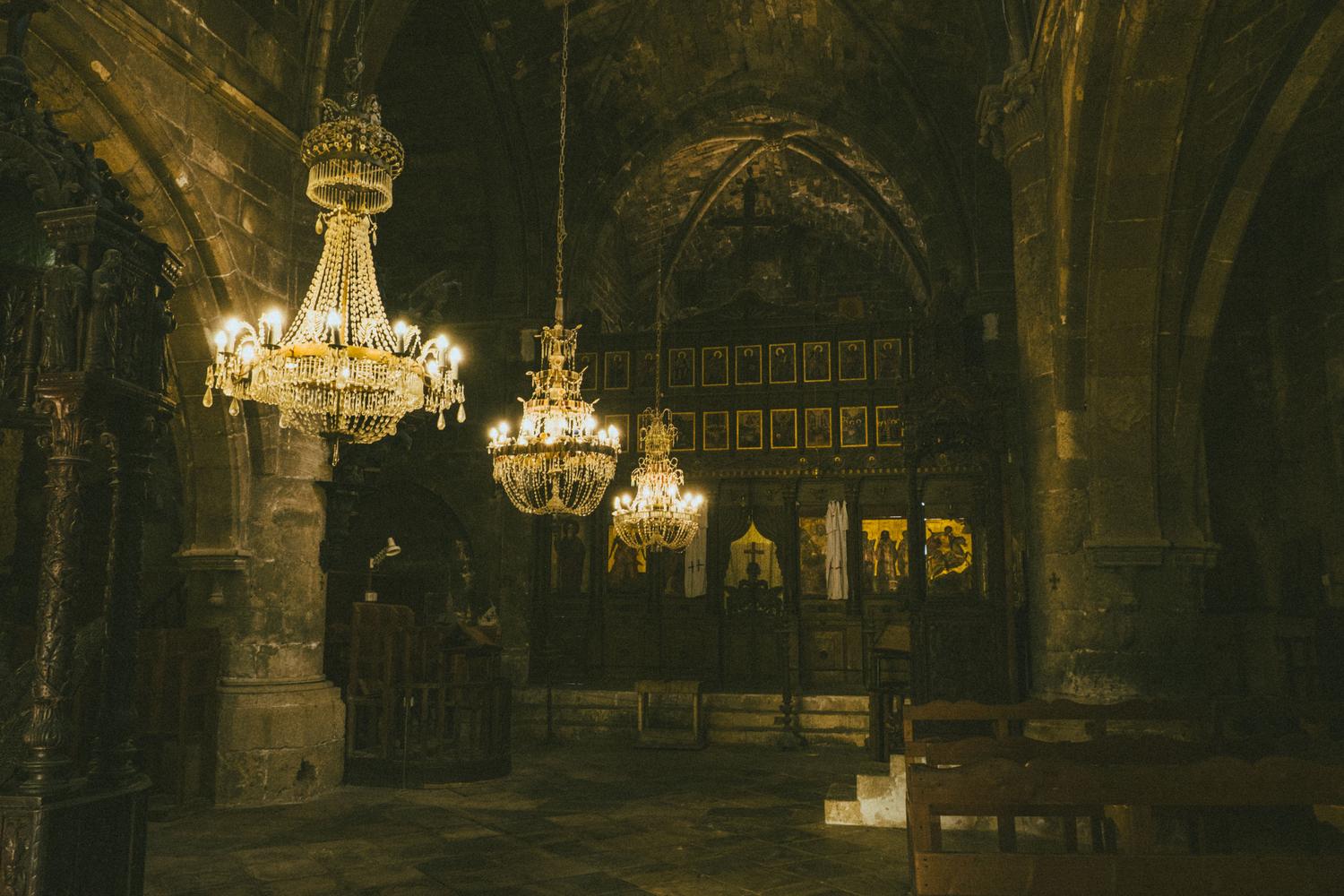 Interior gótico tenuemente iluminado con arquitectura orlada, evocando las ciudades y castillos del mundo de The Witcher.