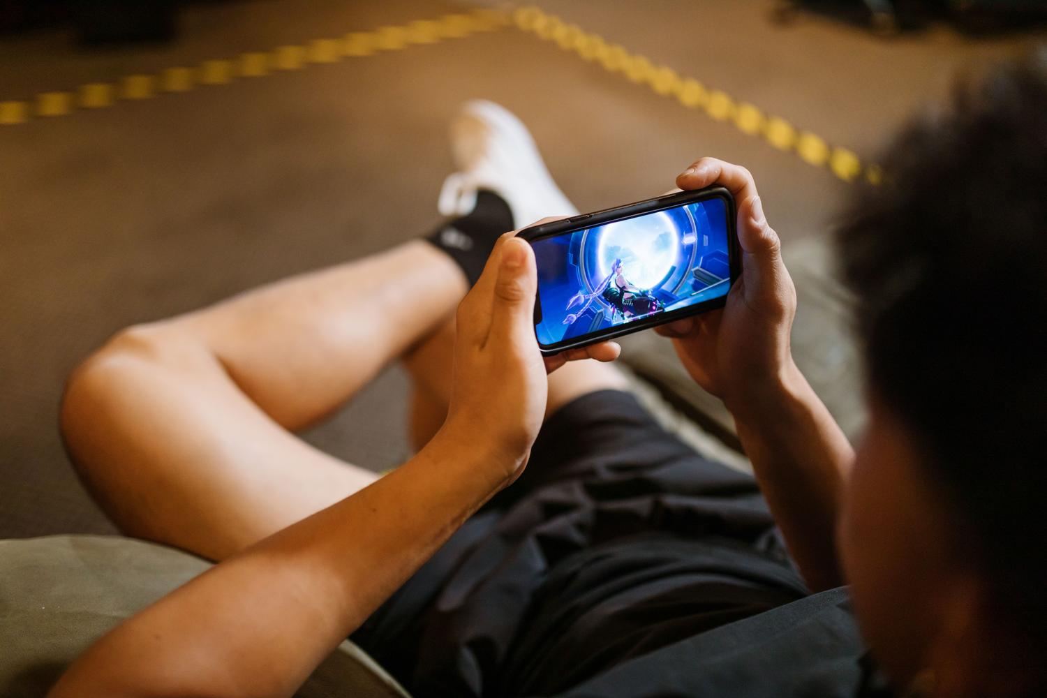 Persona jugando a un videojuego en un móvil Android en modo horizontal, ilustración general de gaming móvil.