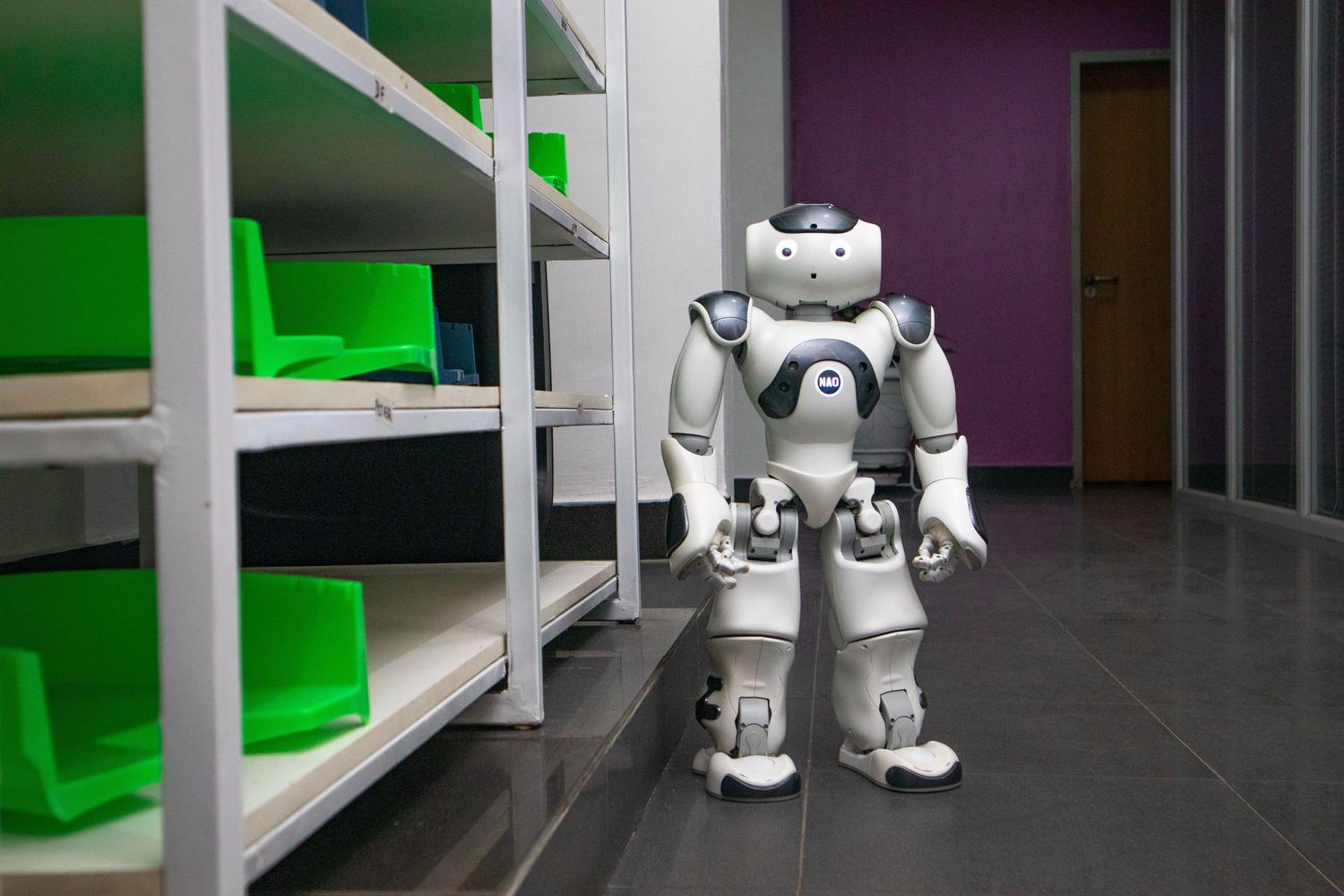 Robot humanoide integrado en un pasillo de almacén con estanterías estandarizadas, simbolizando la Industria 4.0.