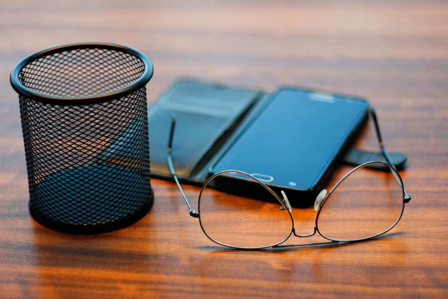 Smartphone y gafas sobre un escritorio de oficina, evocando el entorno de una reunión de trabajo.