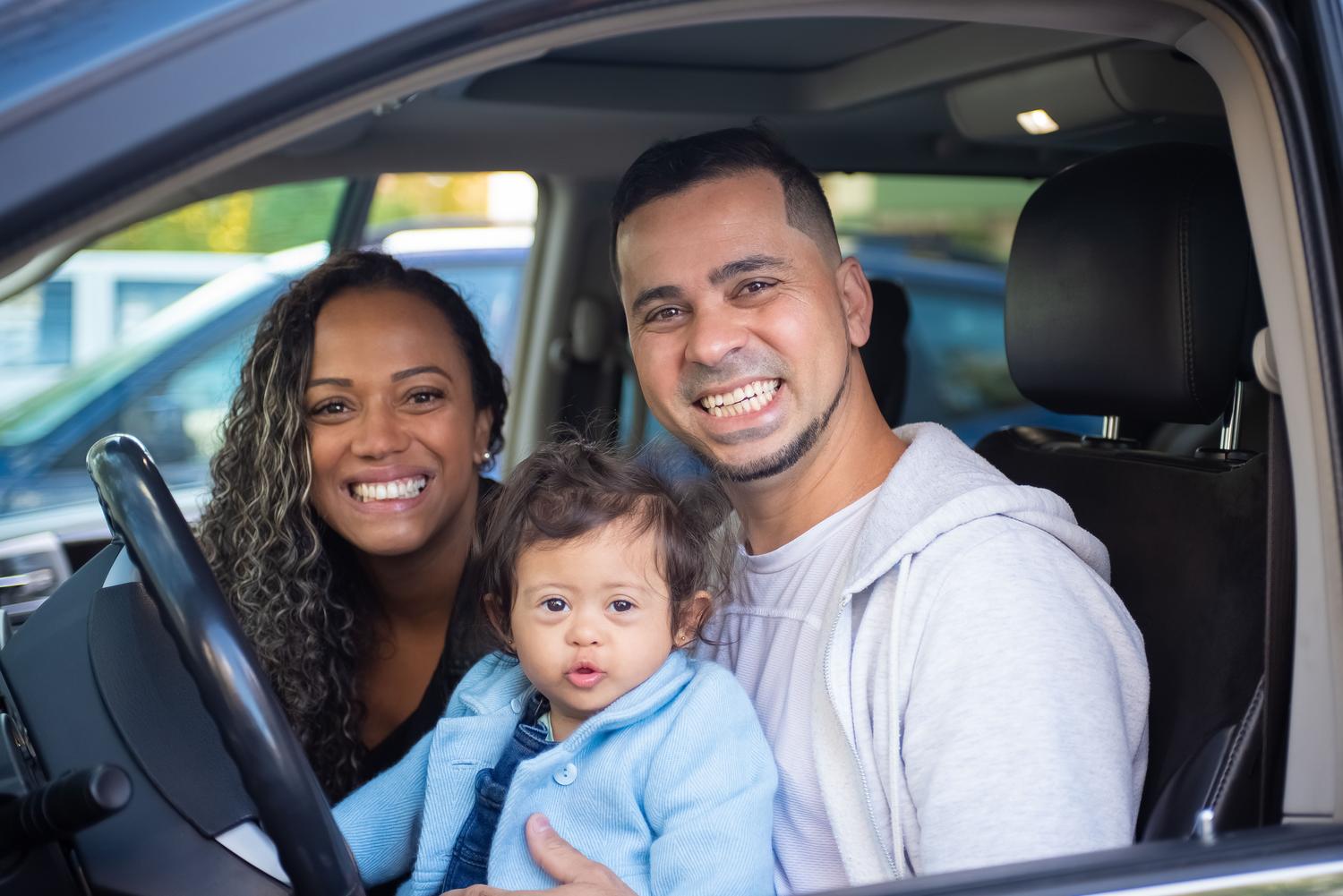 Una familia feliz y sonriente sentada en el interior de un coche, representando el beneficio emocional de regalar un vehículo a familiares directos.