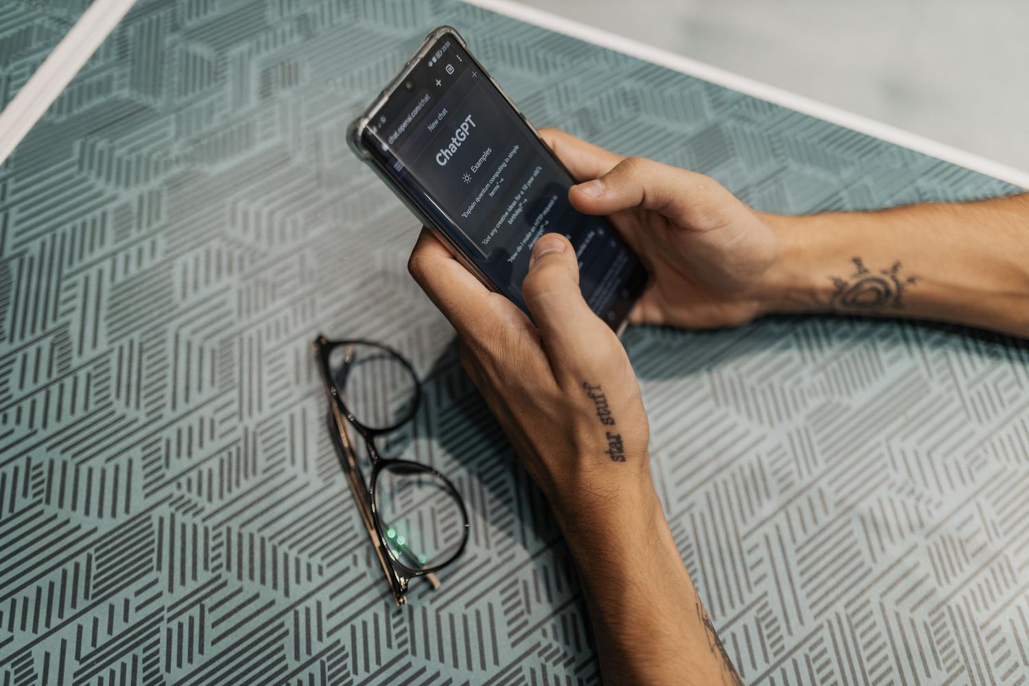 Close-up of a person using the ChatGPT app on a smartphone, linking the AI conversational interface with the virtual clothing feature.