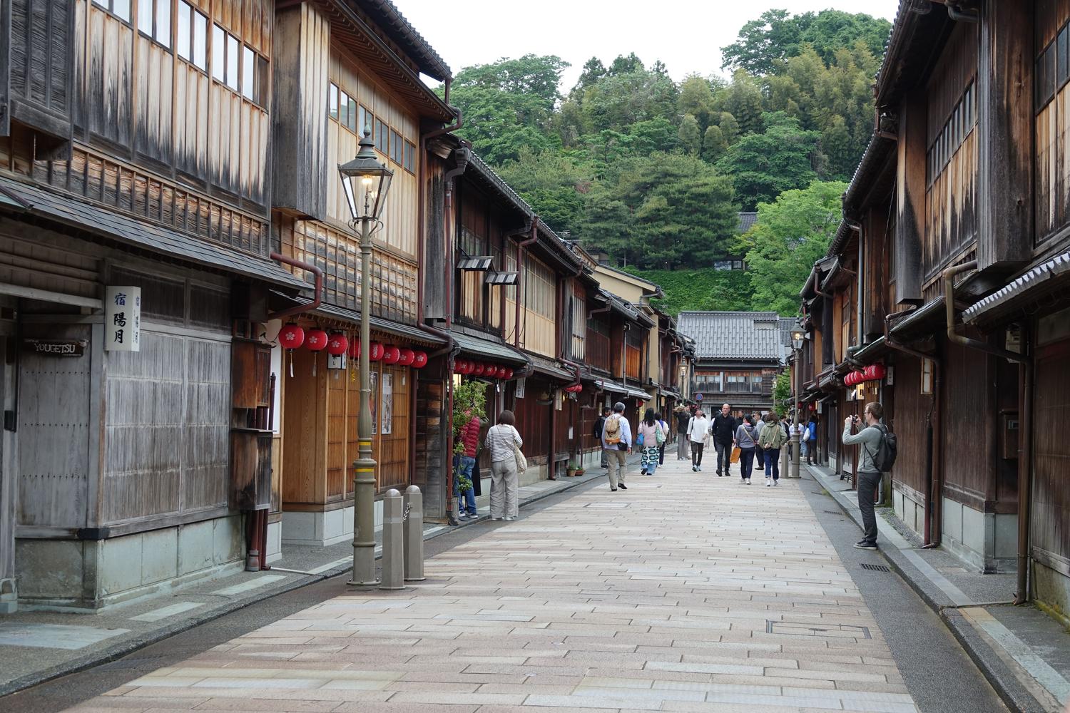 Traditional Japanese street with wooden architecture and red lanterns, mirroring the aesthetic of the Inazuma region.