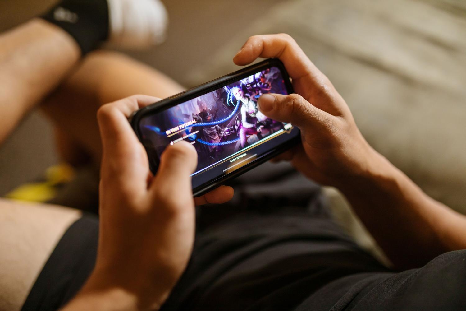 Close-up of a person playing Genshin Impact on a smartphone, highlighting the game's mobile accessibility.