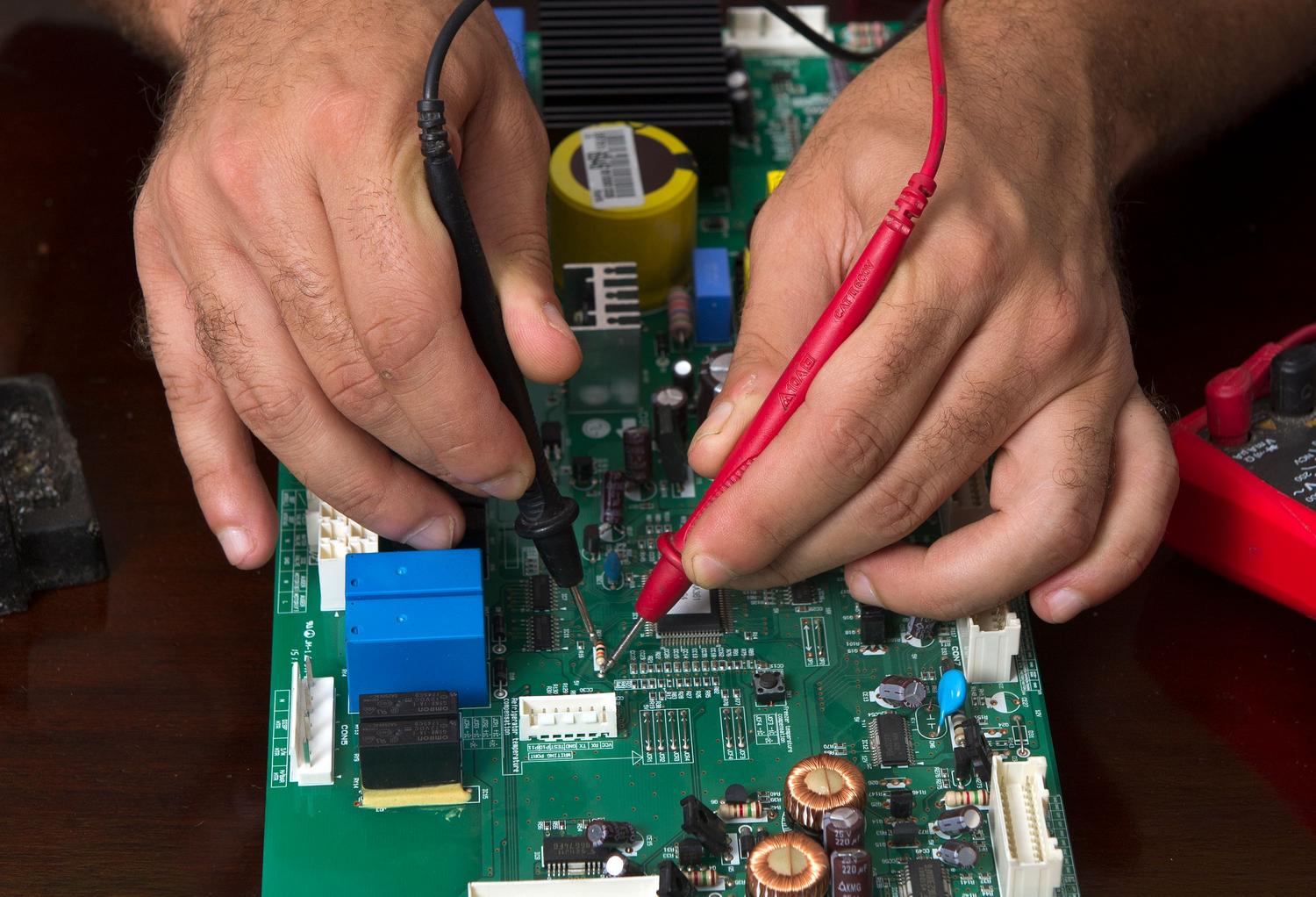 Técnico utilizando las sondas de un multímetro digital para medir el voltaje y diagnosticar problemas en una placa de circuito electrónico.