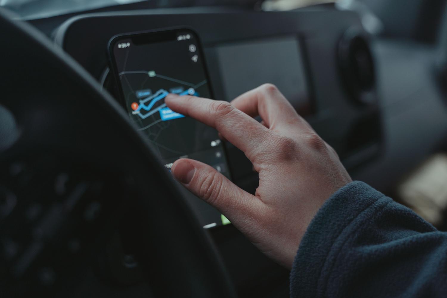 Persona ajustando la navegación GPS en un móvil montado en el interior del coche.