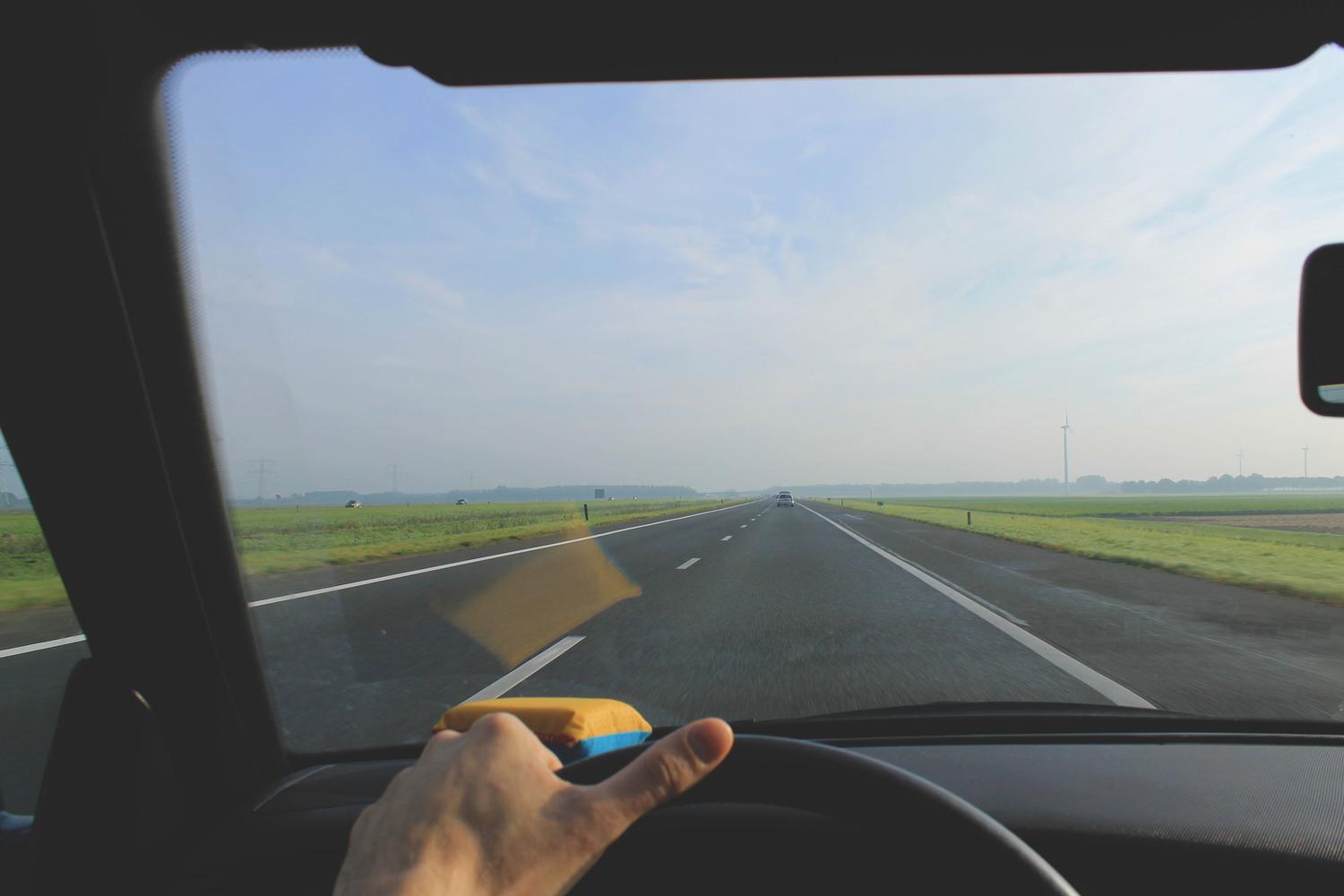 Vista desde el interior de un coche circulando por una autopista despejada y soleada, escenario ideal para el uso del regulador de velocidad.