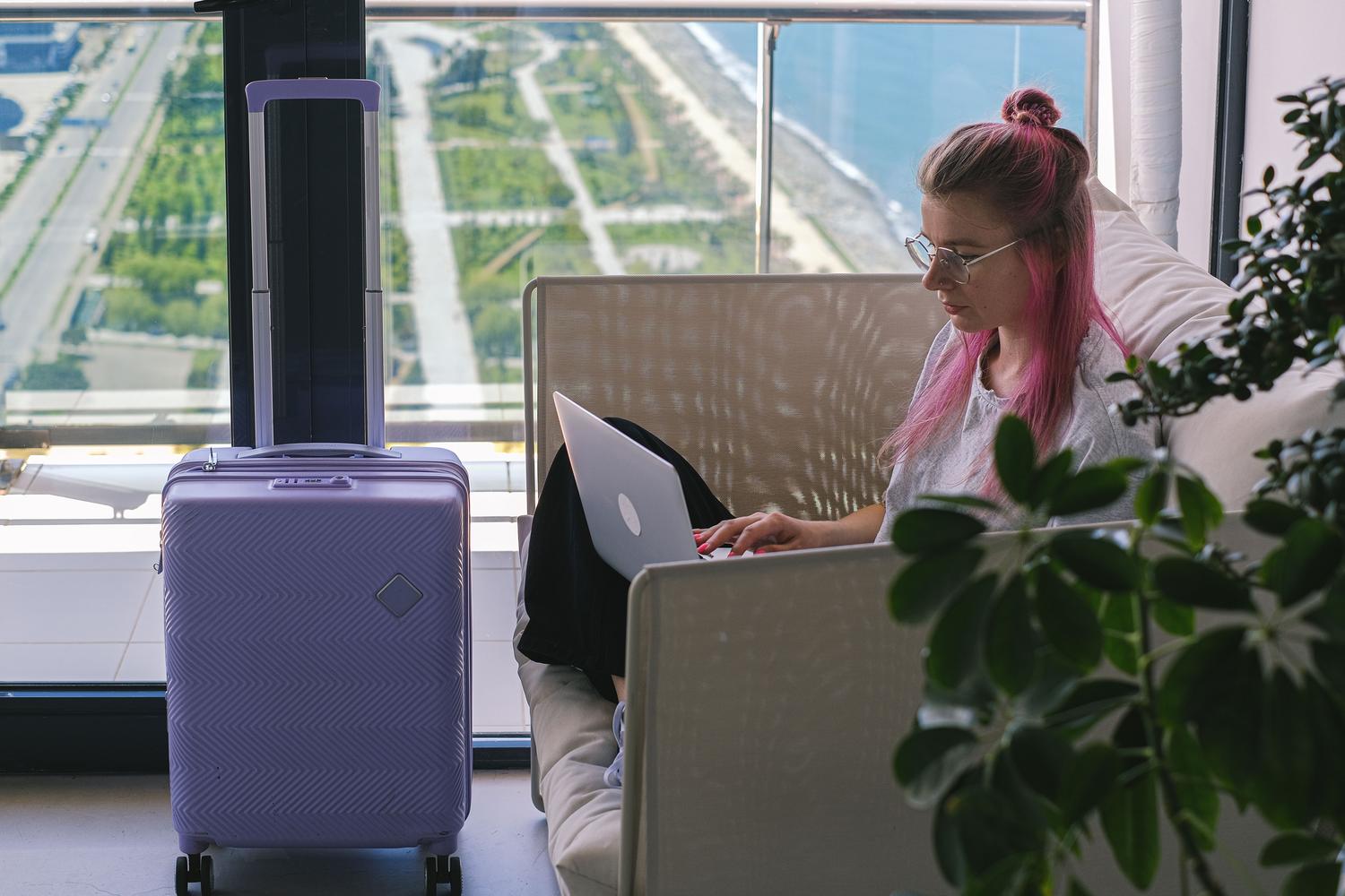 Mujer trabajando freelance con portátil en una habitación de hotel con vistas