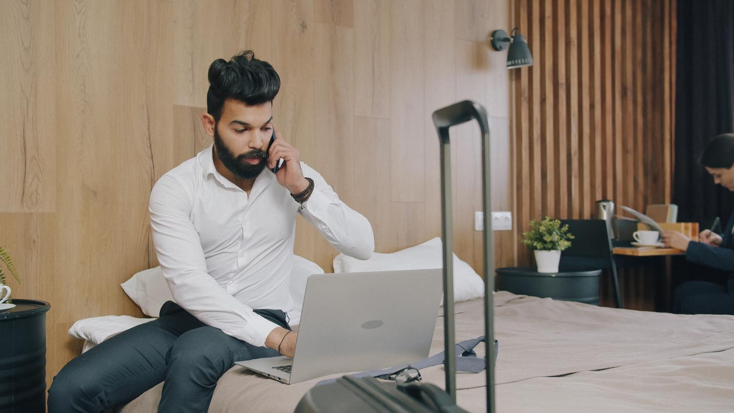 Hombre de negocios trabajando remotamente con su portátil en una habitación de hotel