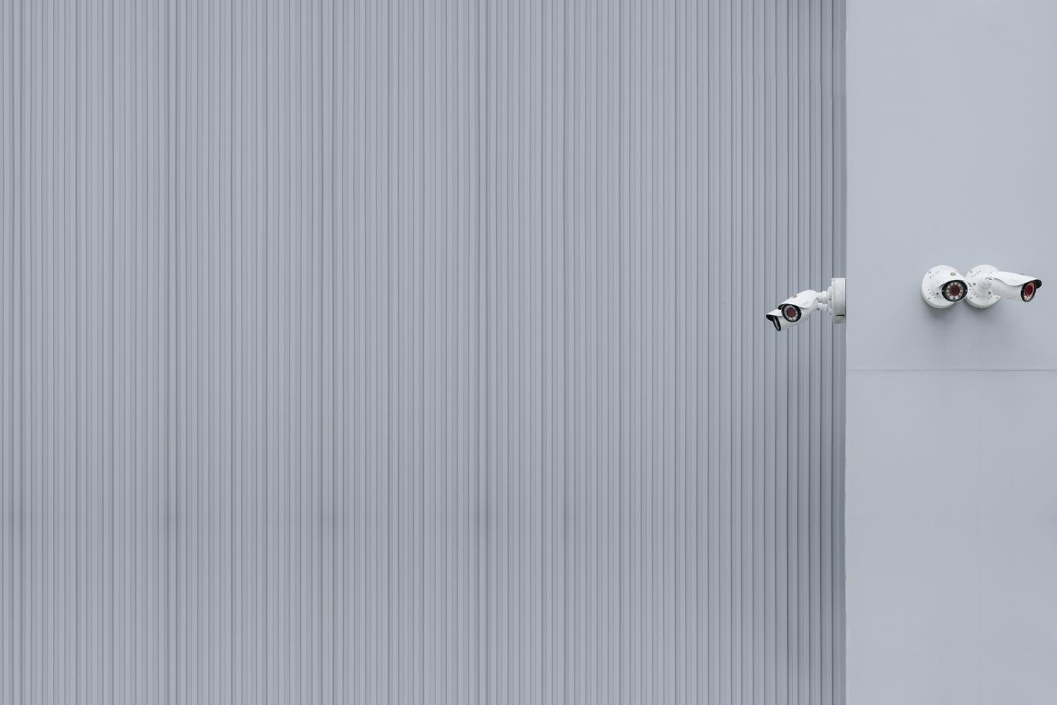 Cámaras de vigilancia en una pared gris, ilustrando los vectores de ataque en entornos corporativos.