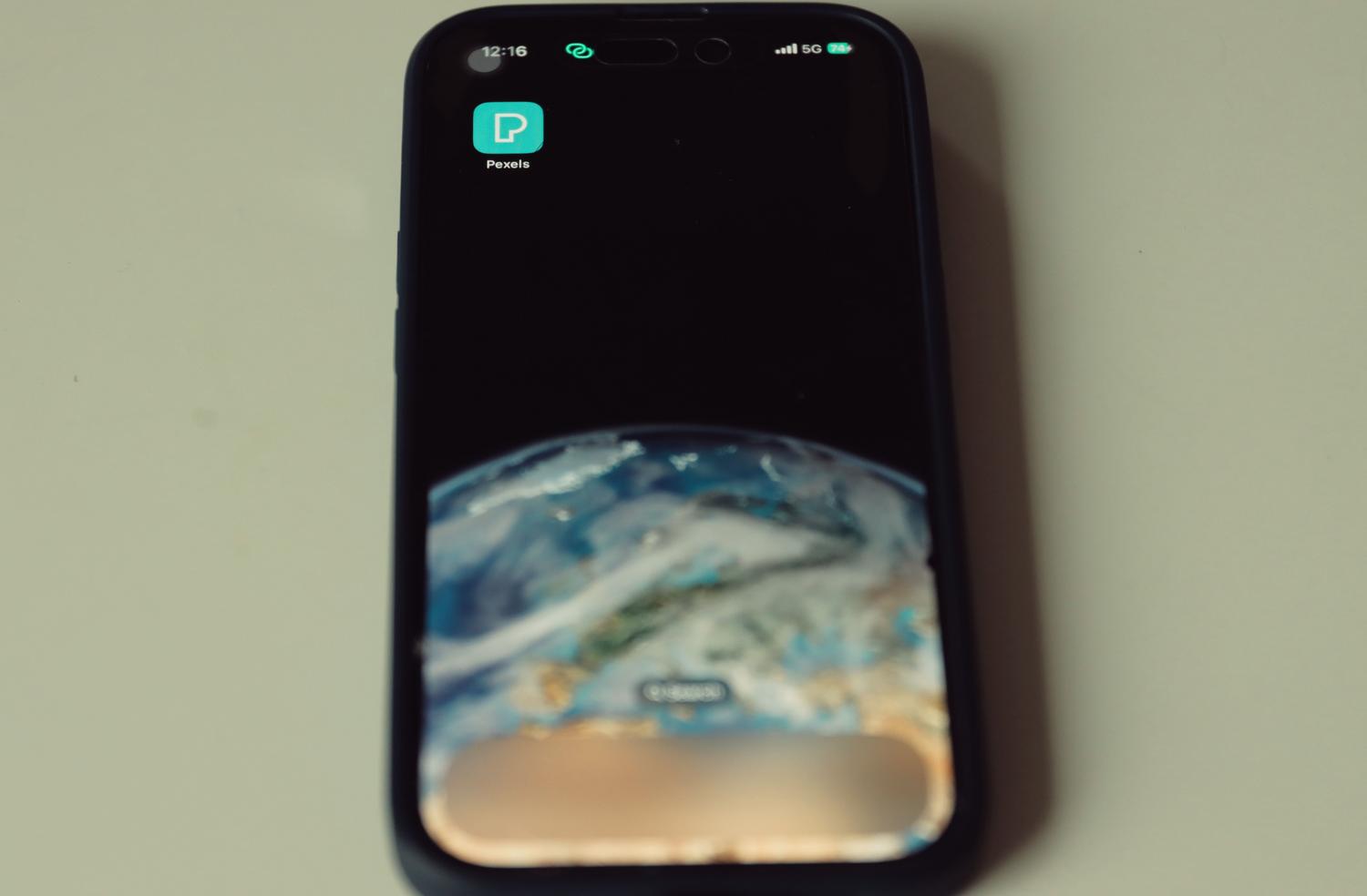 Smartphone mostrando un fondo de pantalla de la Tierra y el indicador de red 5G, simbolizando la conectividad global instantánea.