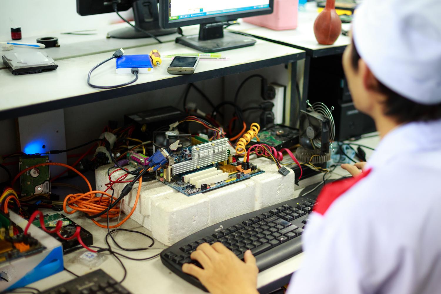 Técnico de ingeniería electrónica trabajando en el ensamblaje y diagnóstico de una placa base en un laboratorio.