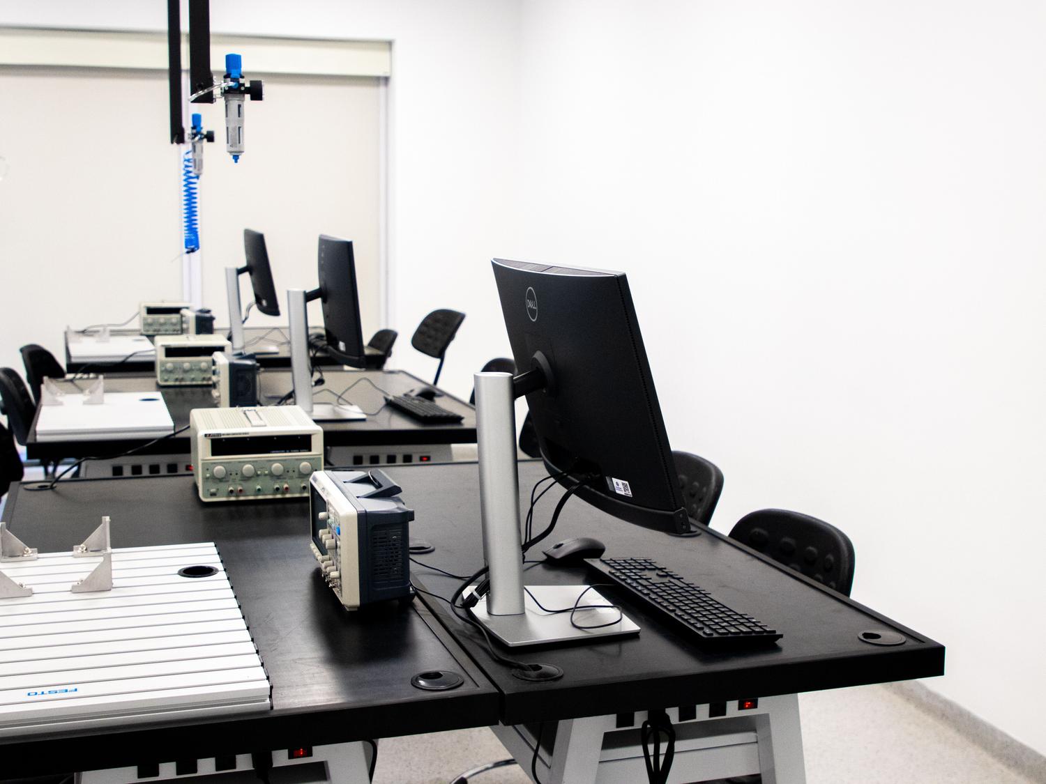 Laboratorio de ingeniería moderno equipado con múltiples estaciones de trabajo y equipos de medición técnica.
