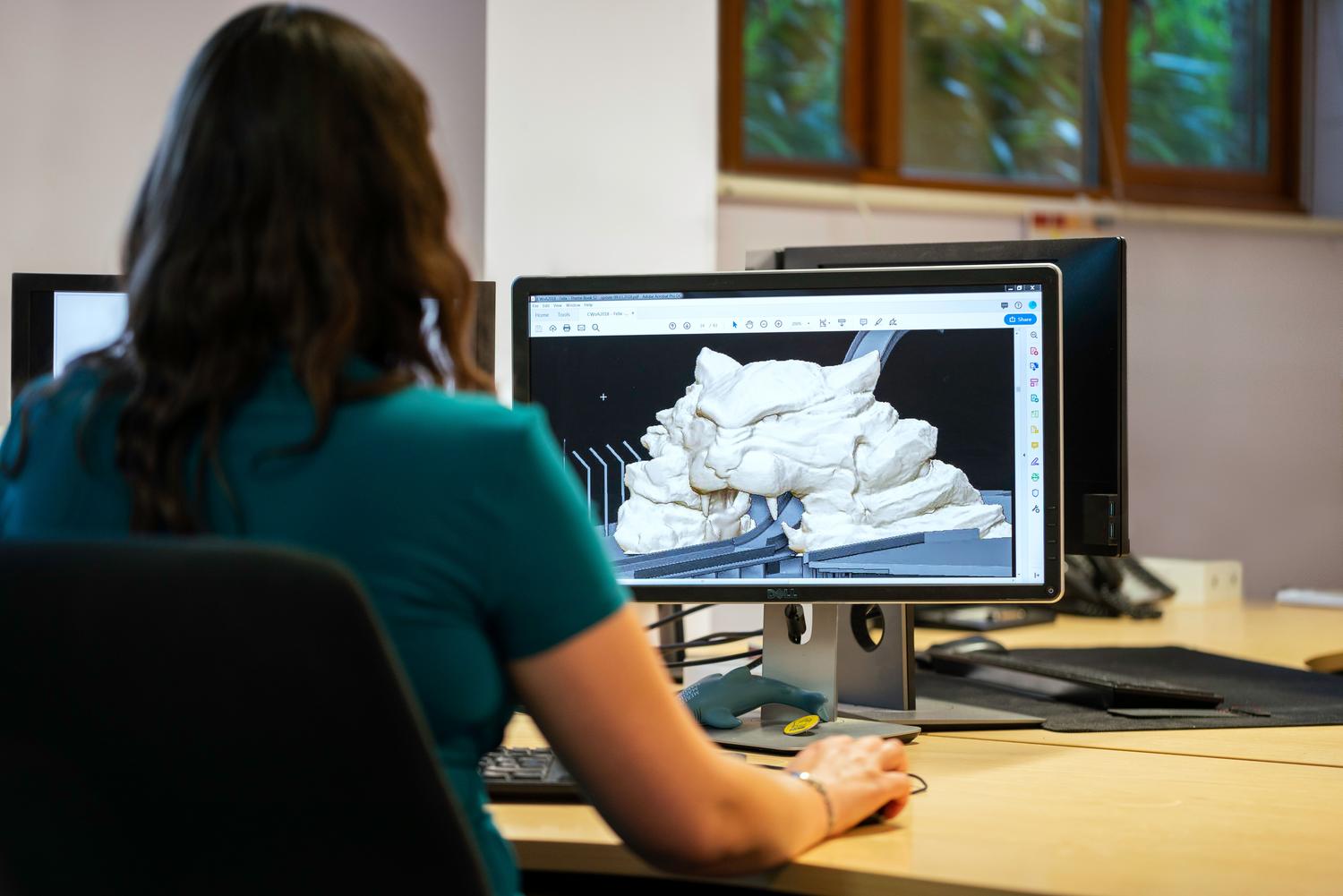 Ingeniera utilizando software CAD para modelado 3D de una pieza compleja en una estación de trabajo profesional.