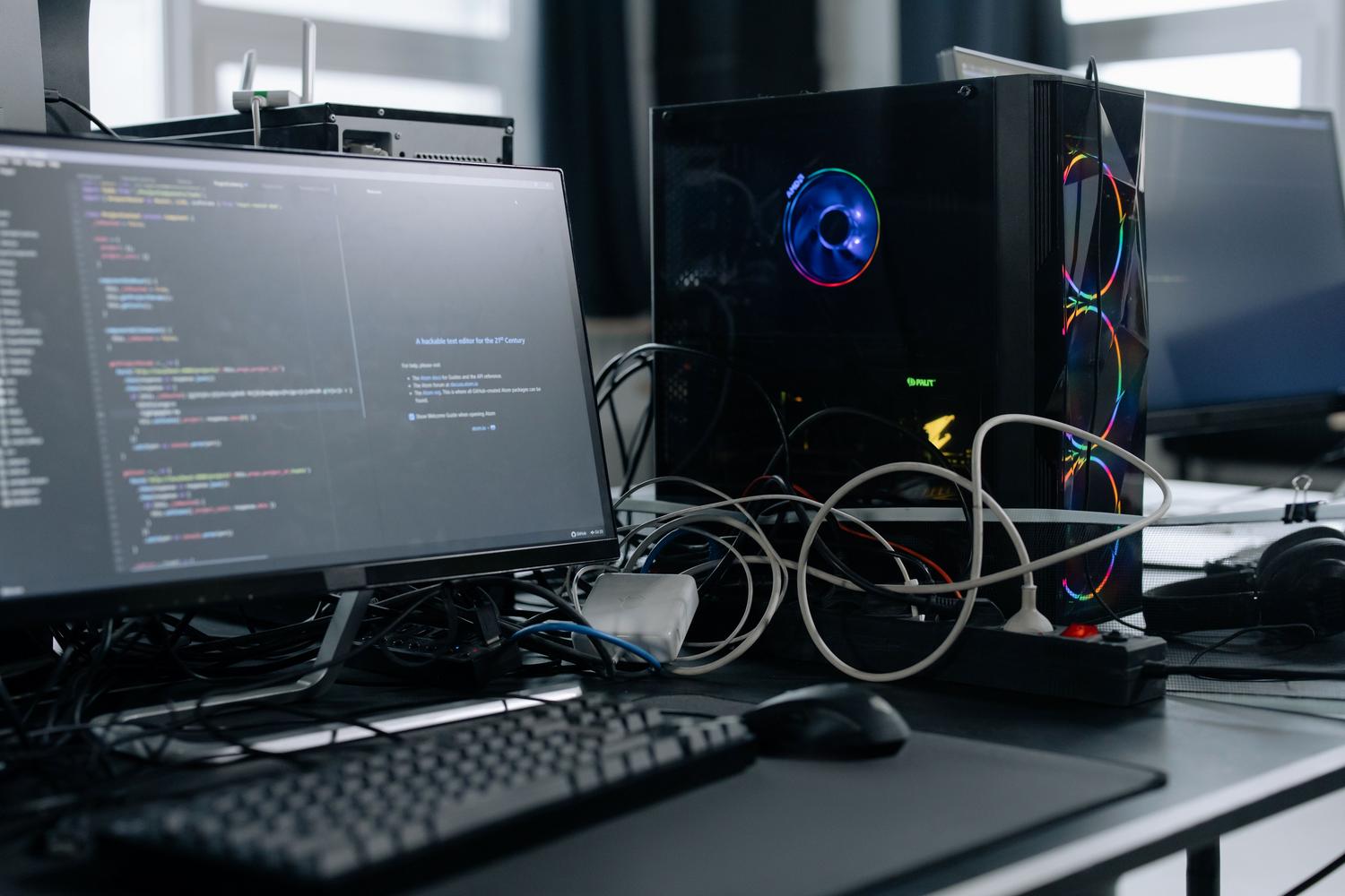 Estación de trabajo de alto rendimiento con torre de PC y monitor mostrando código de programación para simulaciones.